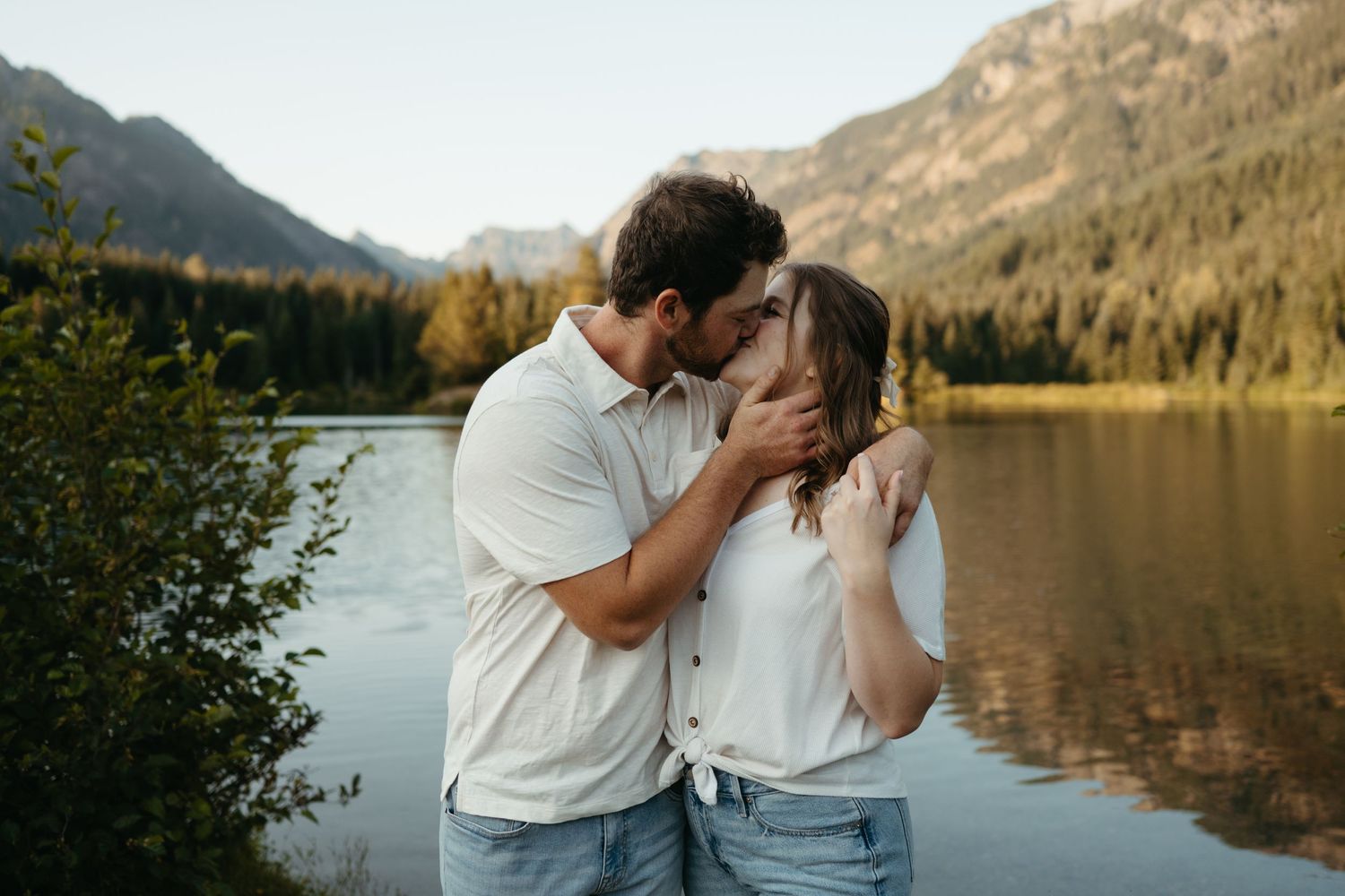 Romantic embrace by scenic mountain lake with forest backdrop.