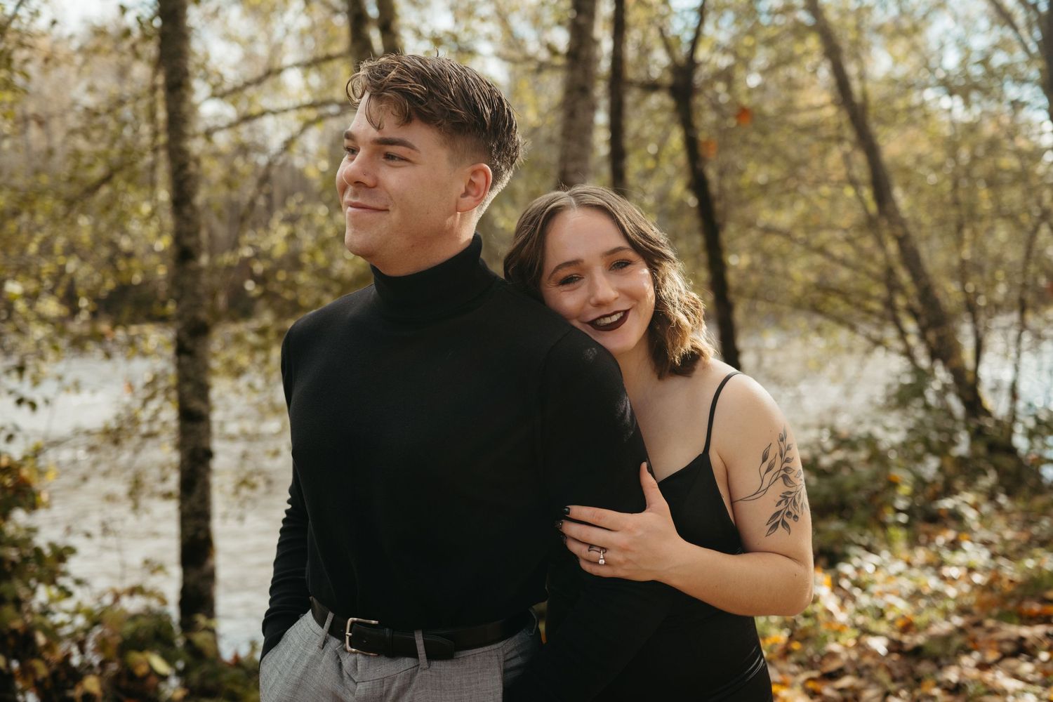 Couple sharing playful moments in an autumn forest setting.