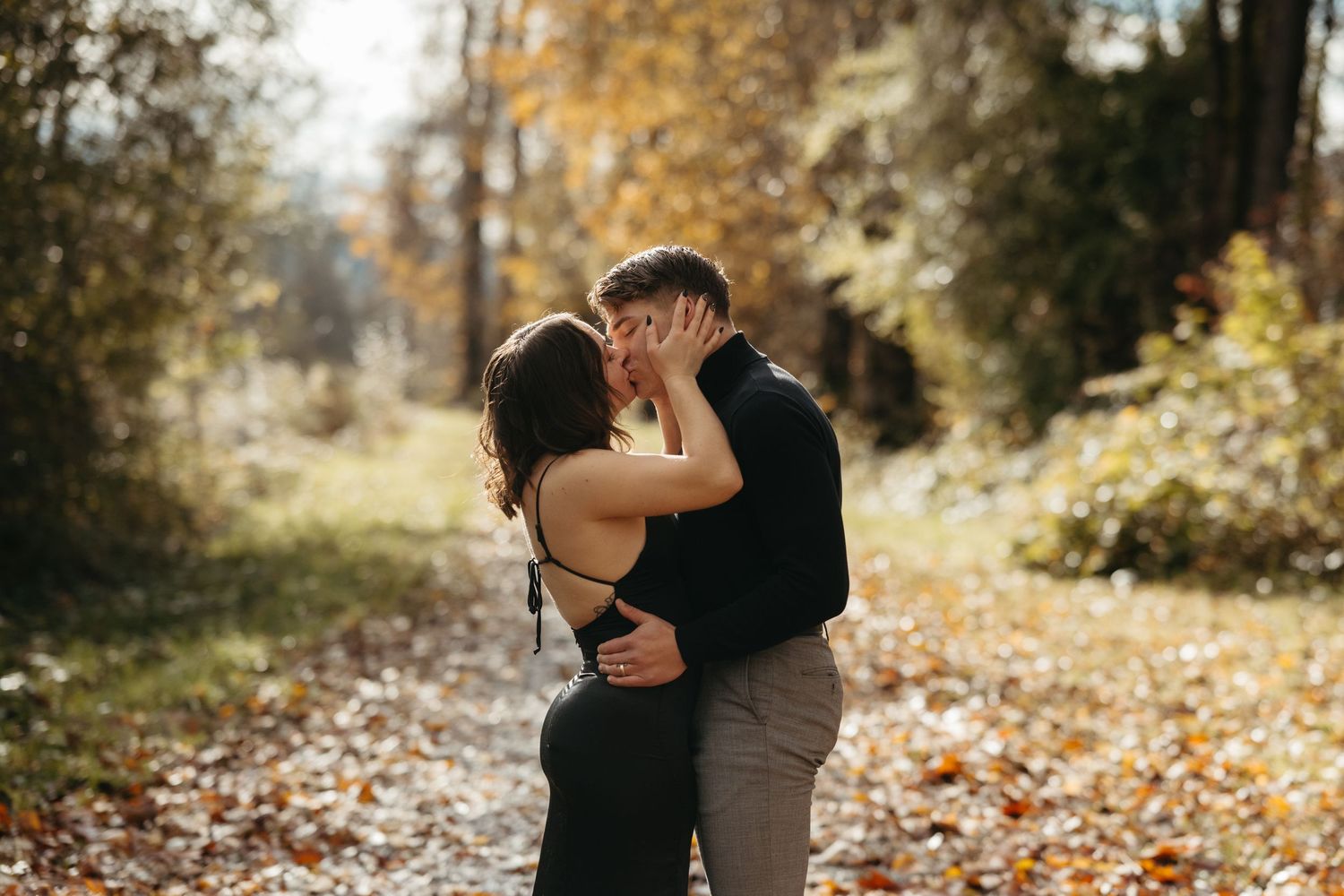 Intimate autumn couples photoshoot with fallen leaves in a wooded setting.