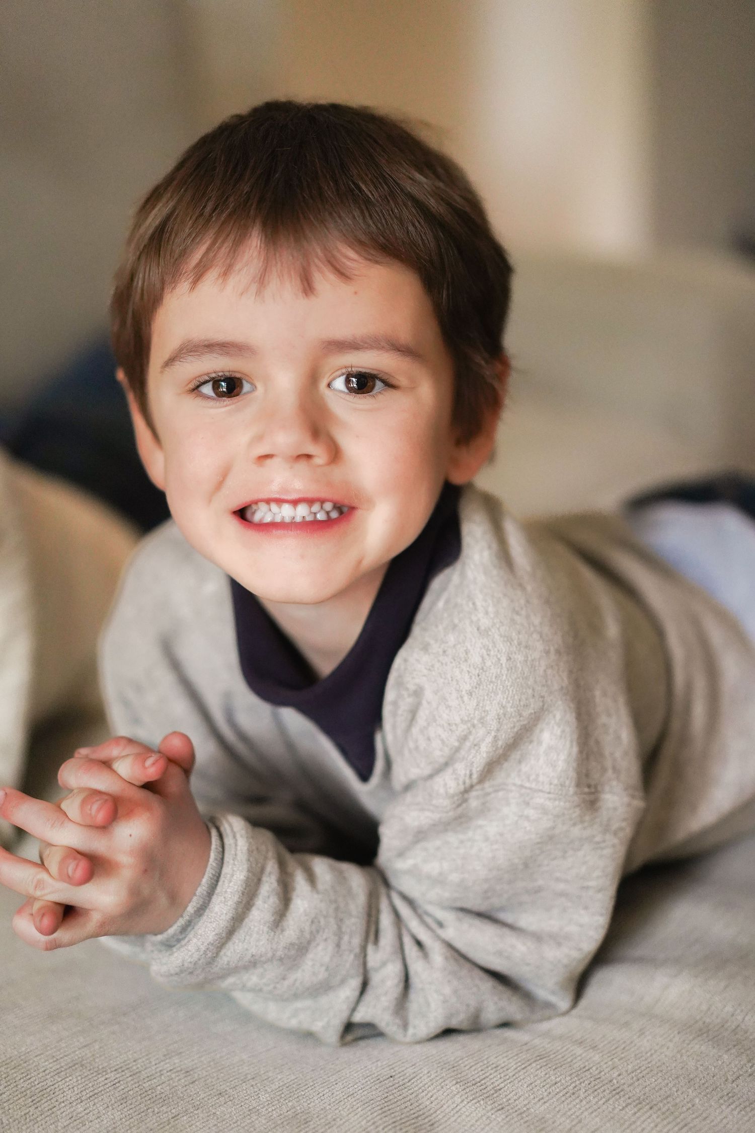 Portrait series showing playful poses in gray sweater on light background.