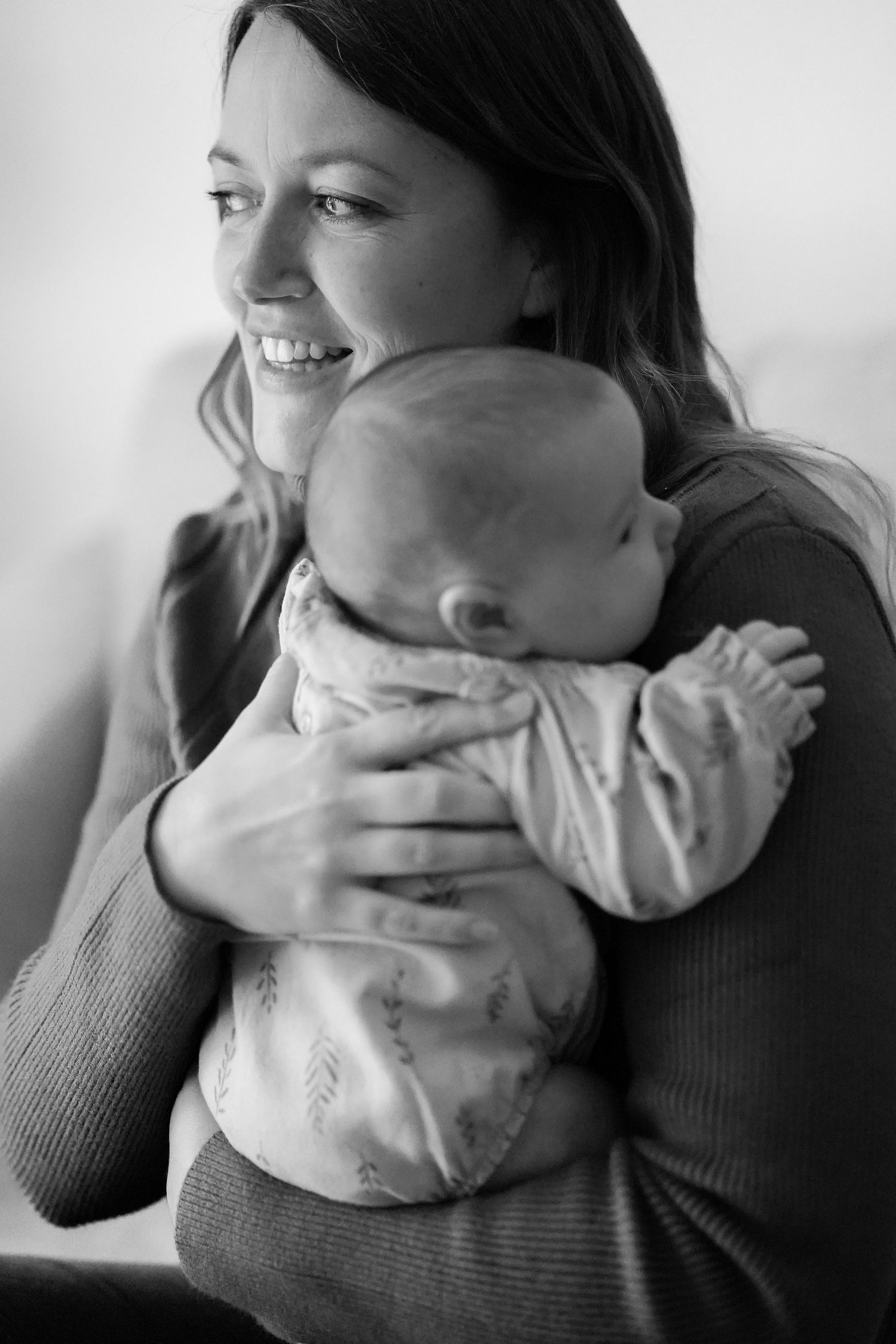 Black and white portrait of woman holding baby in gentle embrace.
