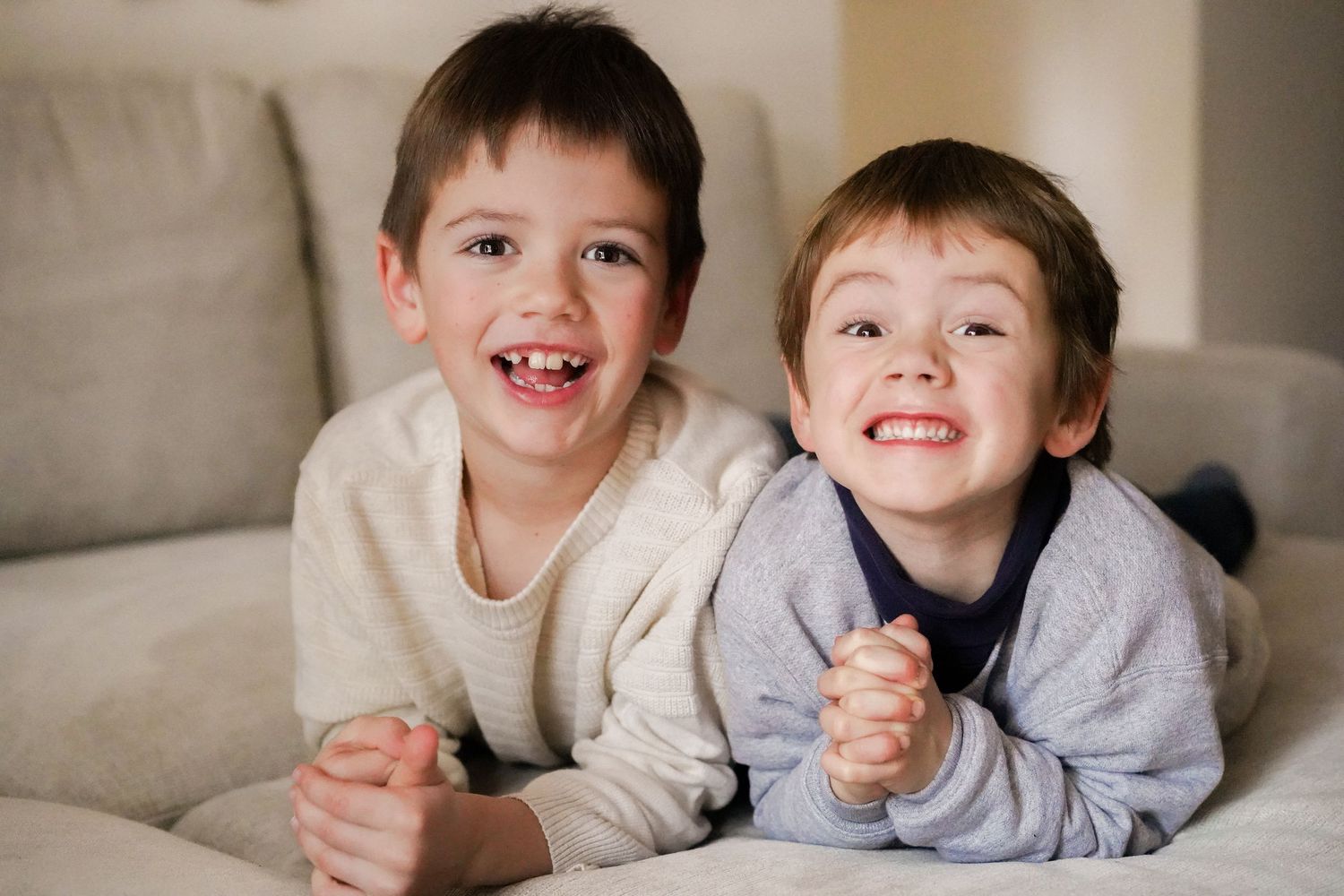 Two children lying together on couch sharing happy moments.