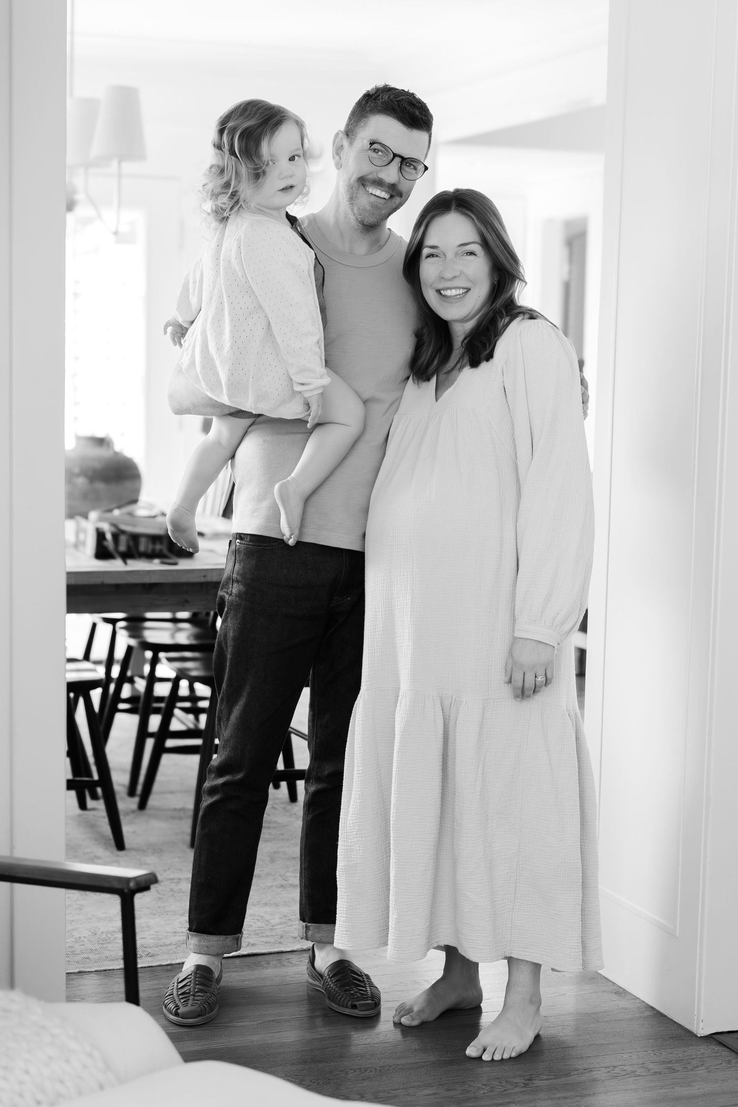 A family portrait in black and white showing three people standing together in a bright room.
