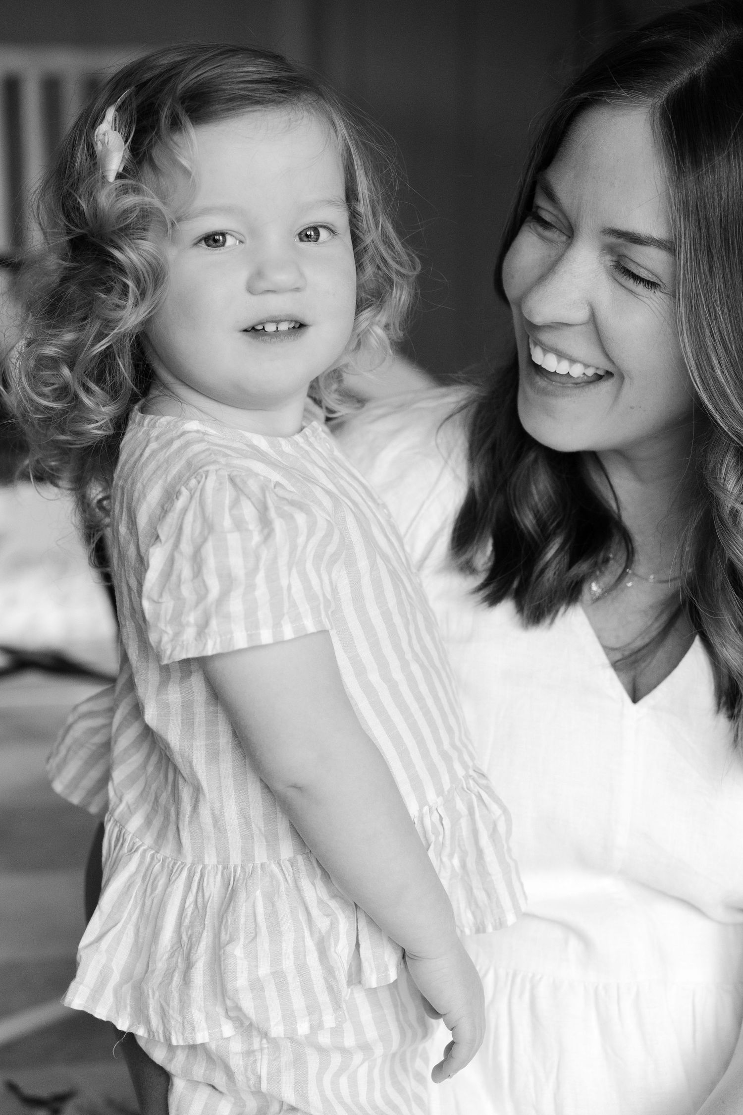 Black and white portrait series showing joyful moments between parent and child in white outfits.