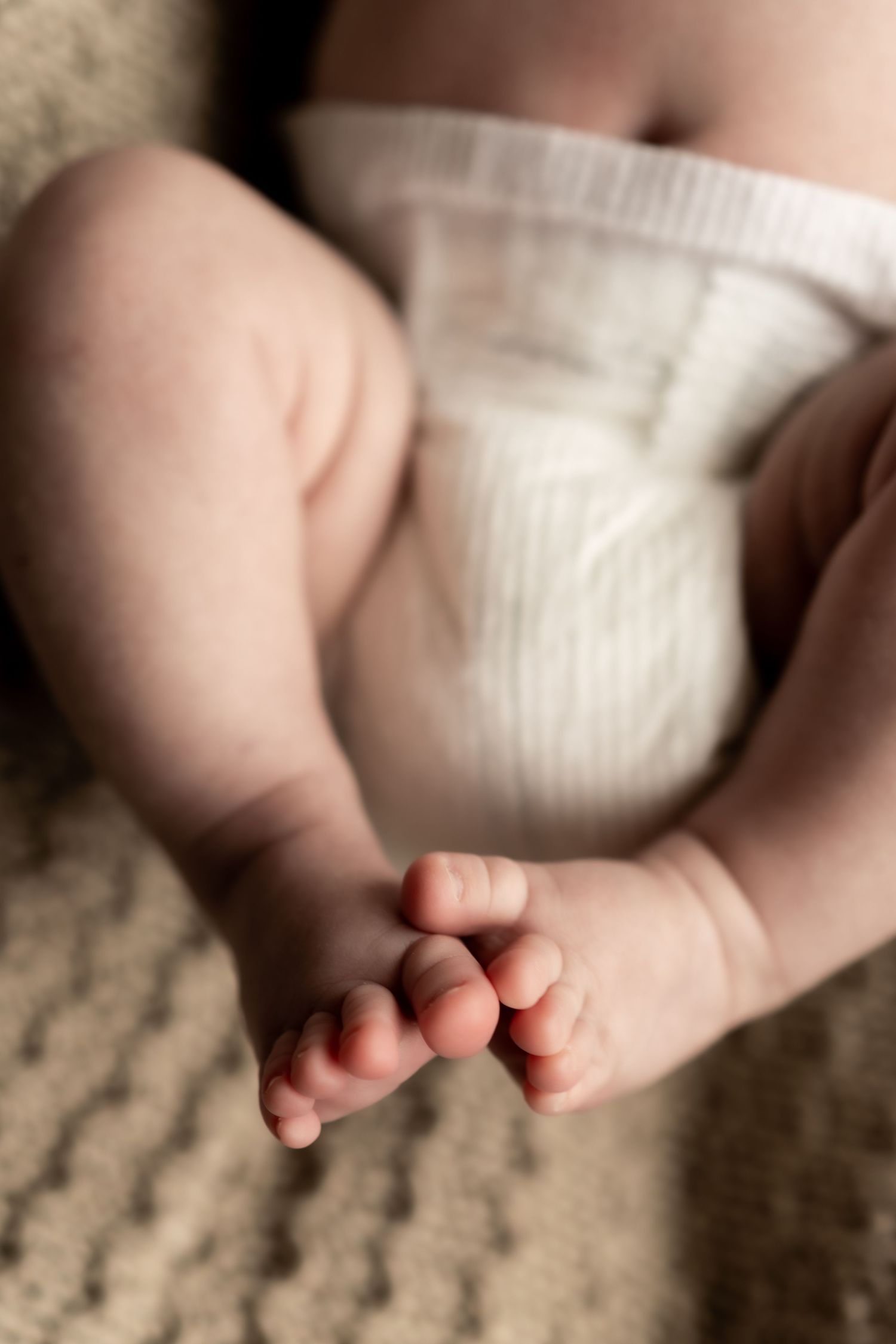 Close-up of tiny baby feet against a soft textured background.