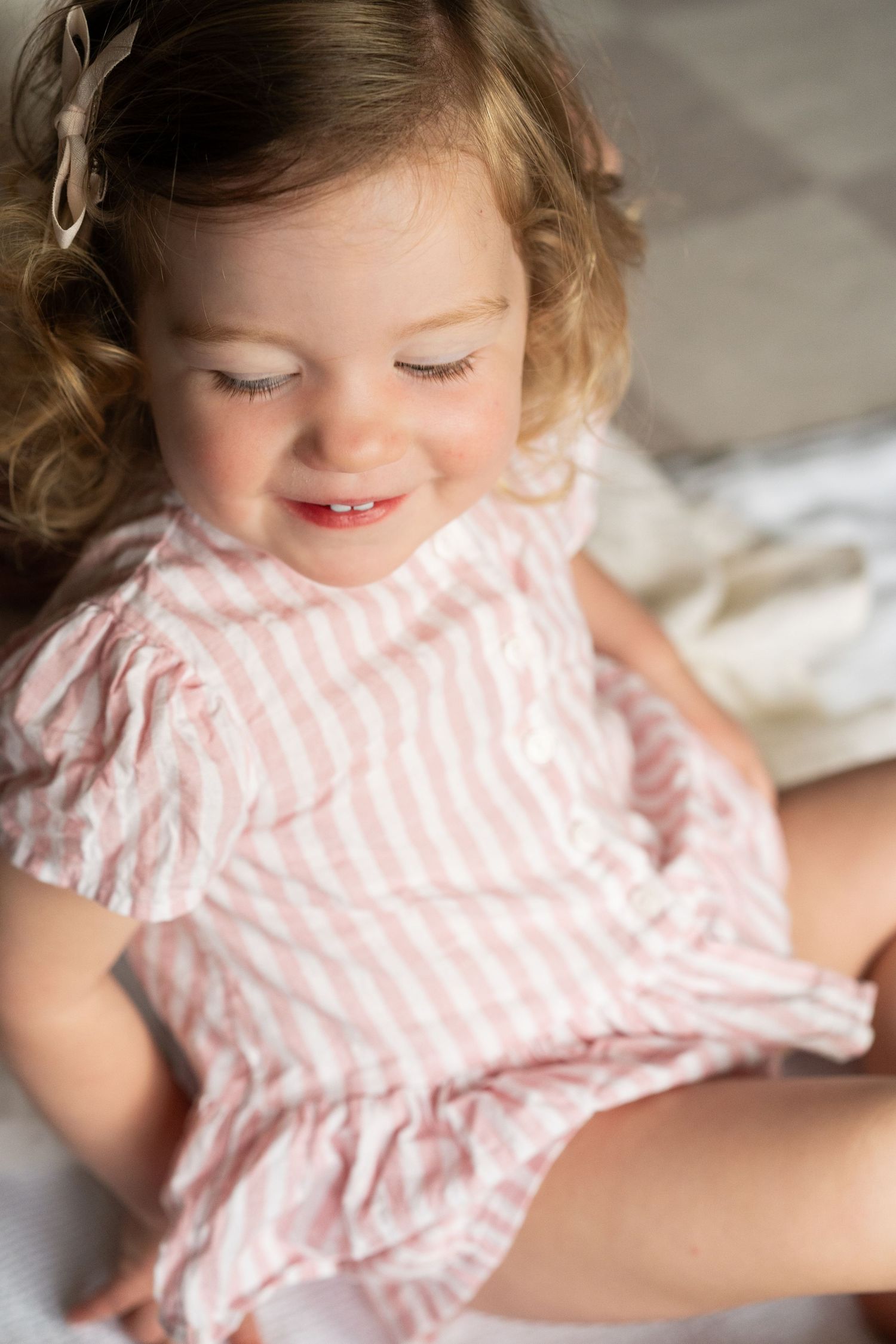 Series of close-up shots showing a young child in pink striped dress playing and smiling.