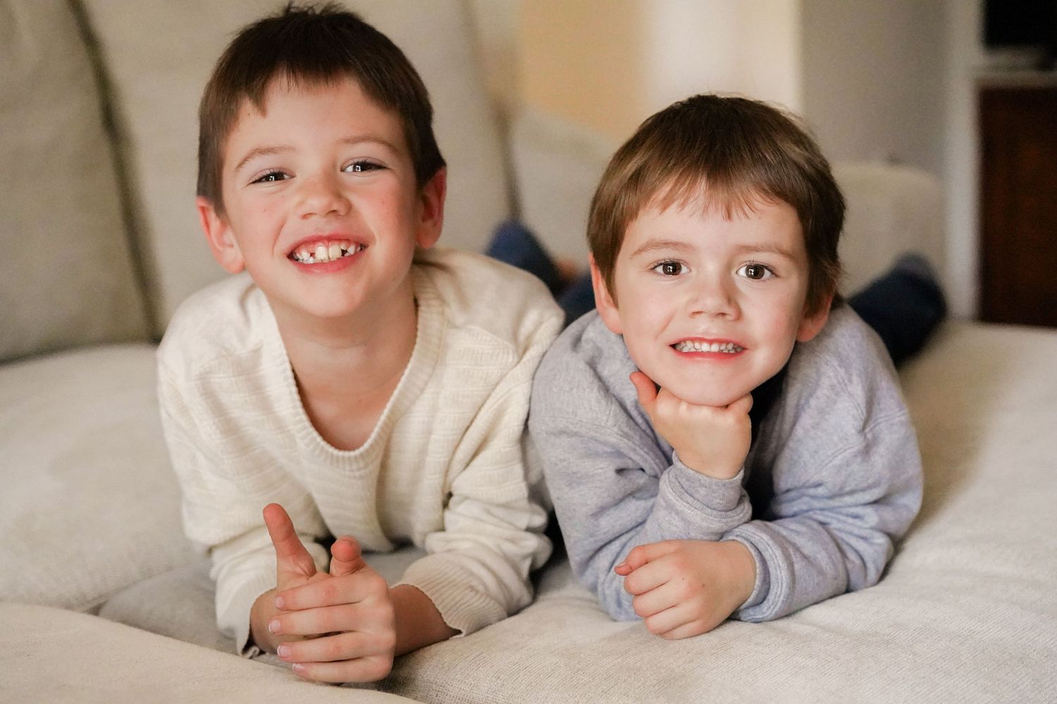 Siblings posing together on couch in coordinating sweaters.