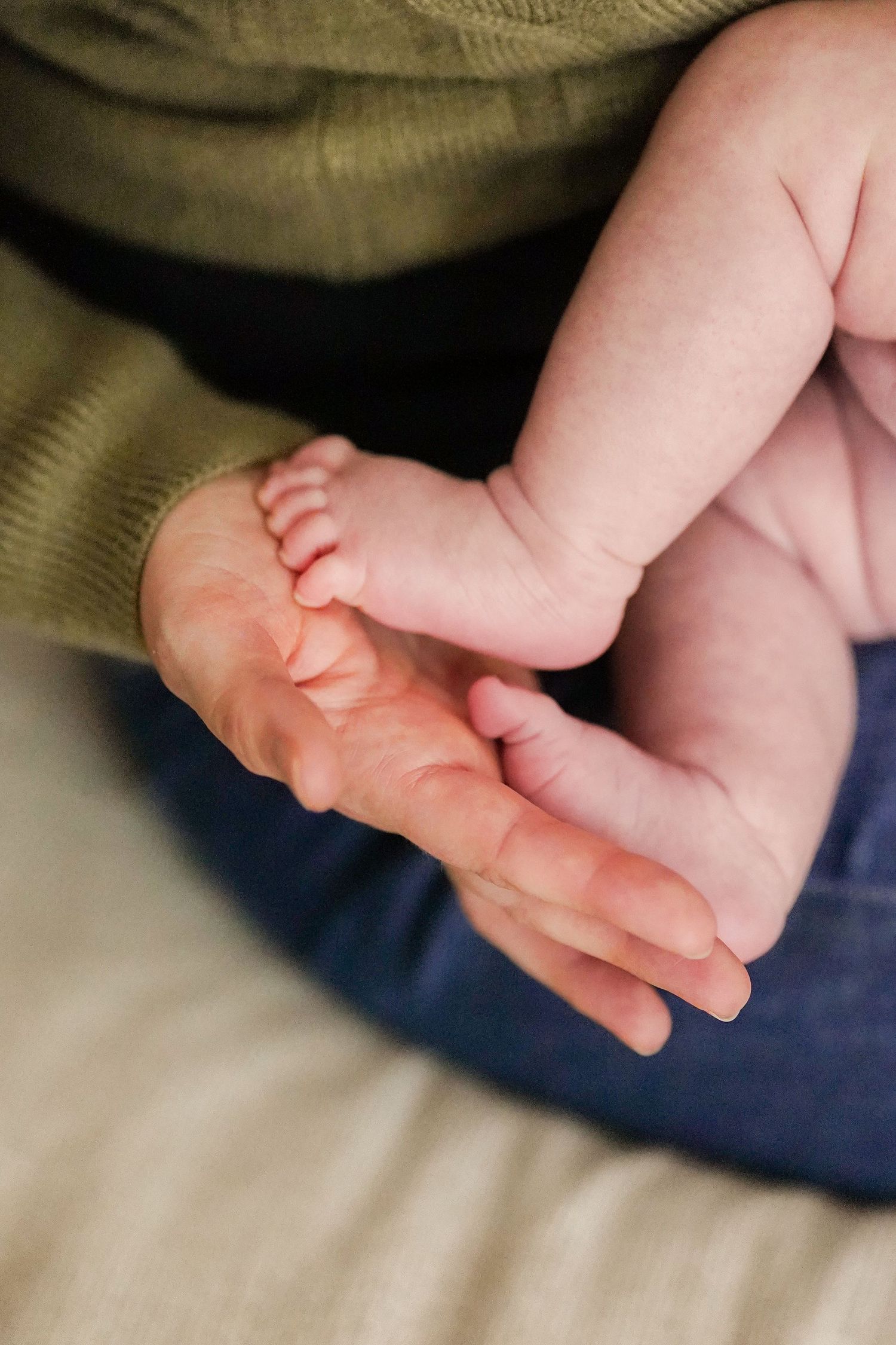 Close-up of baby feet resting on dark blue fabric showing delicate skin tones and tiny toes.