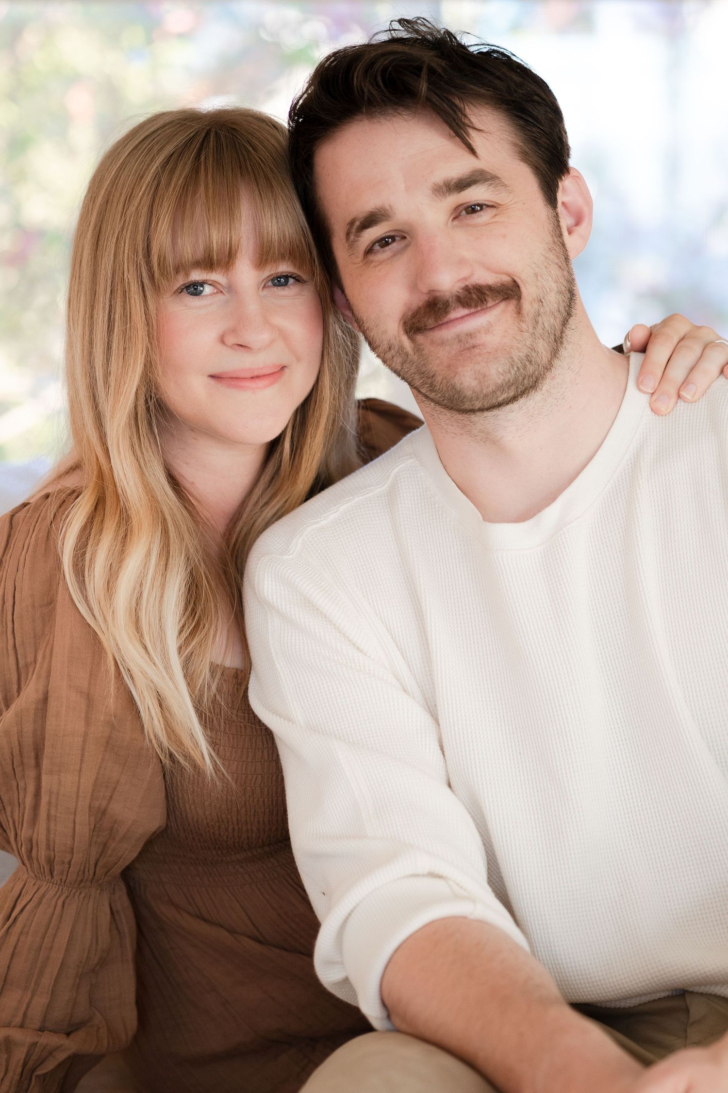 Romantic couple portraits in soft lighting wearing brown and white clothing.