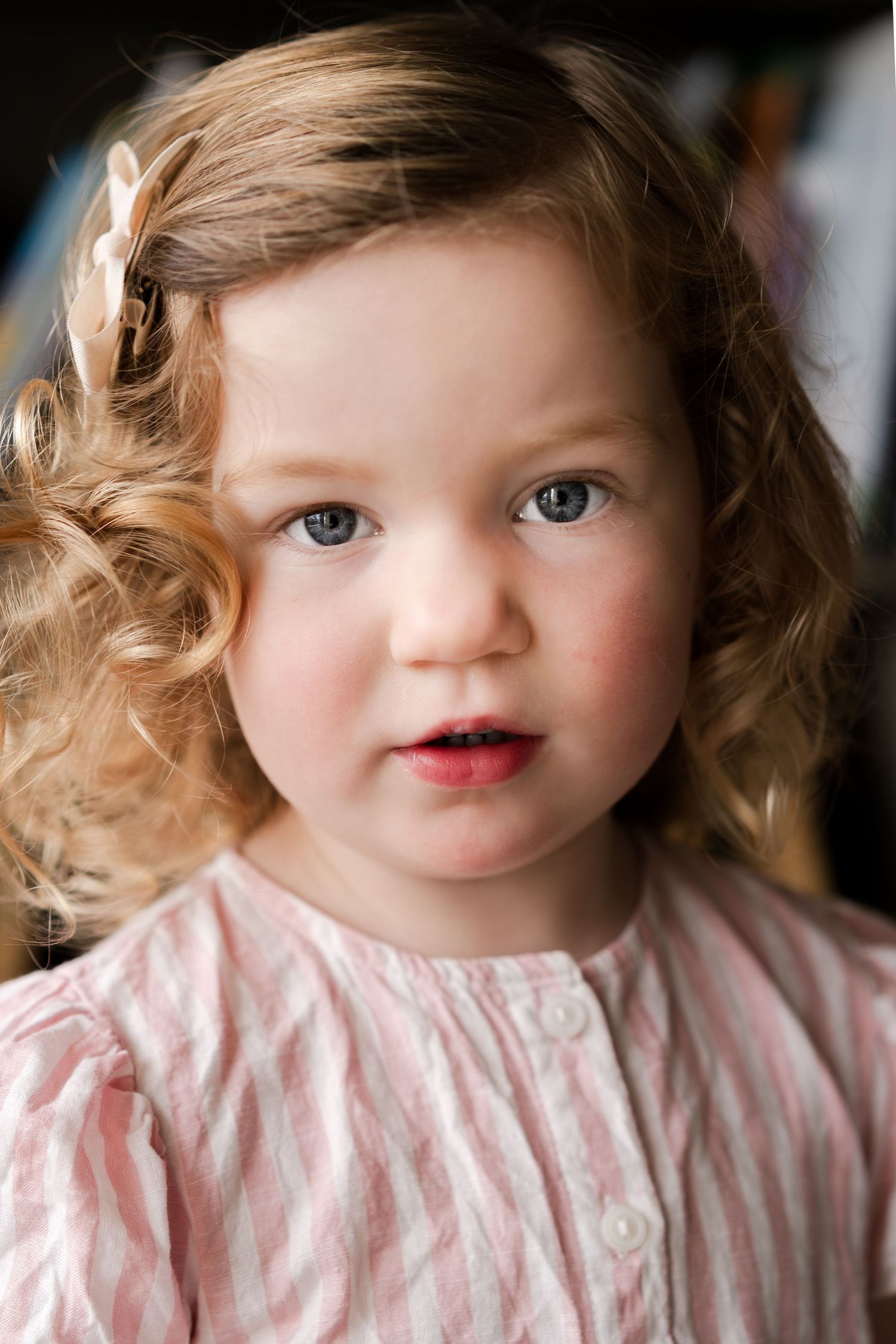 Close-up portrait of a toddler wearing a pink and white striped dress.