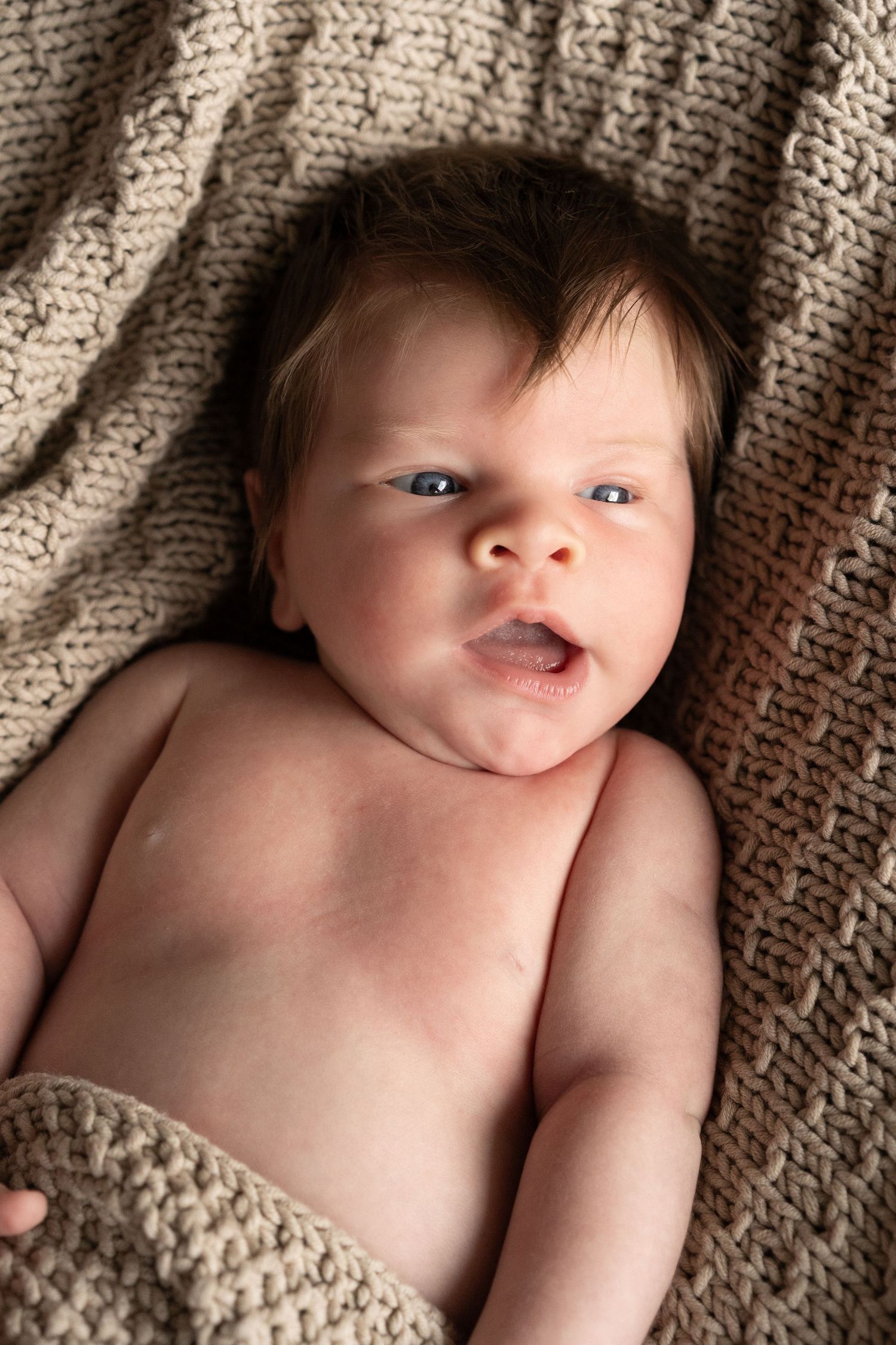 A series of five close-up photos showing a baby lying on a textured brown blanket.