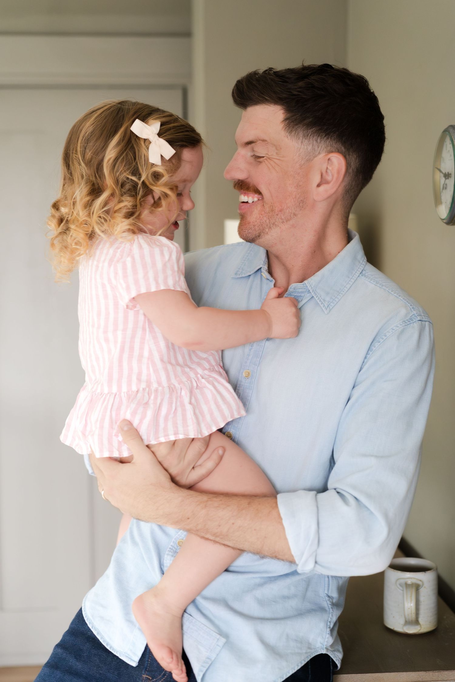 A sweet moment between a toddler in pink and someone in a blue shirt playing and laughing together.