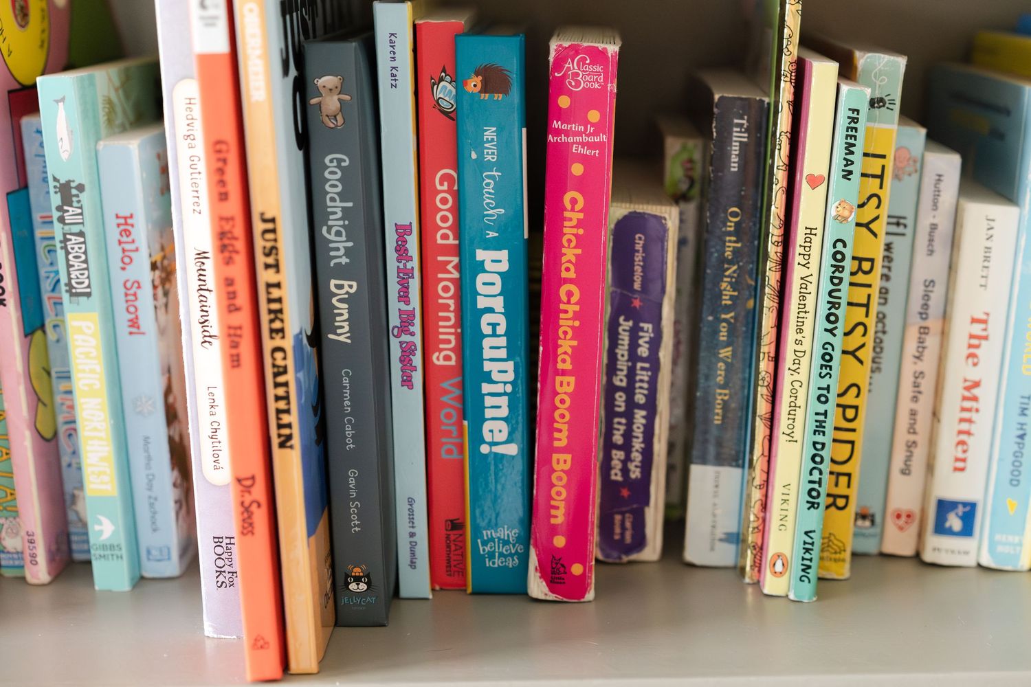 A collection of colorful children's books arranged on a wooden shelf.