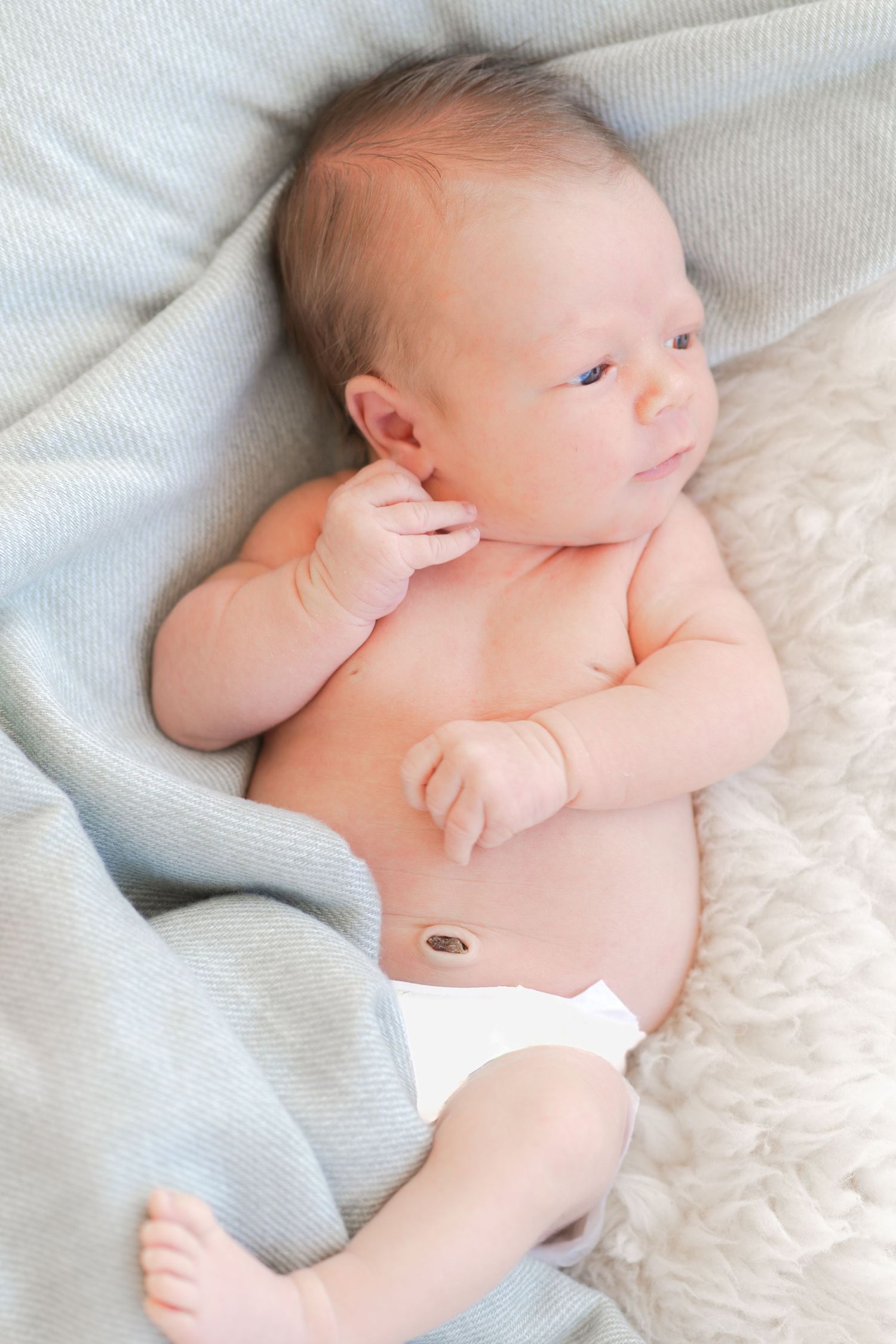 Newborn baby lying on soft white textiles in various poses.