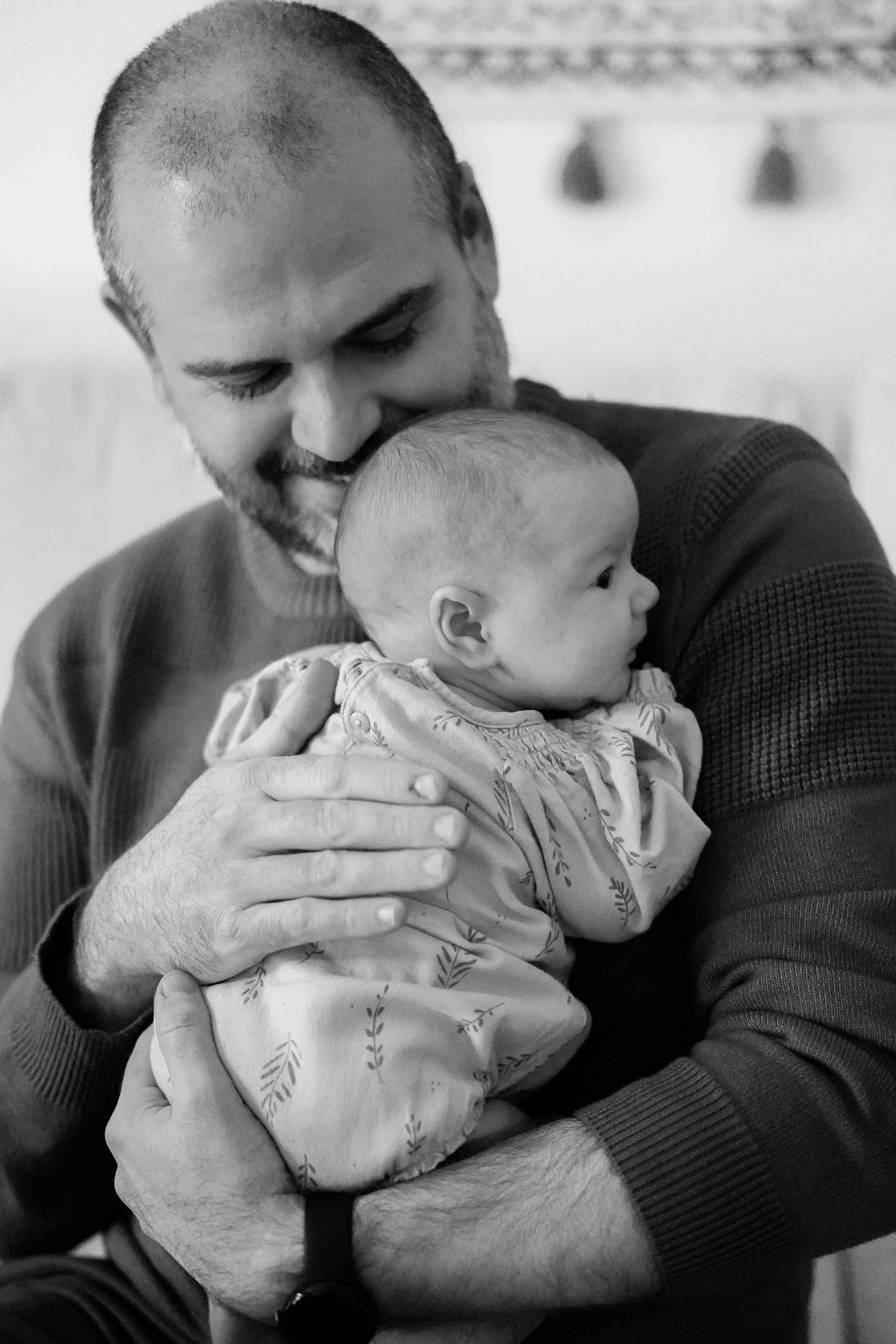 Black and white portrait of tender moment between parent and infant in cozy sweater.