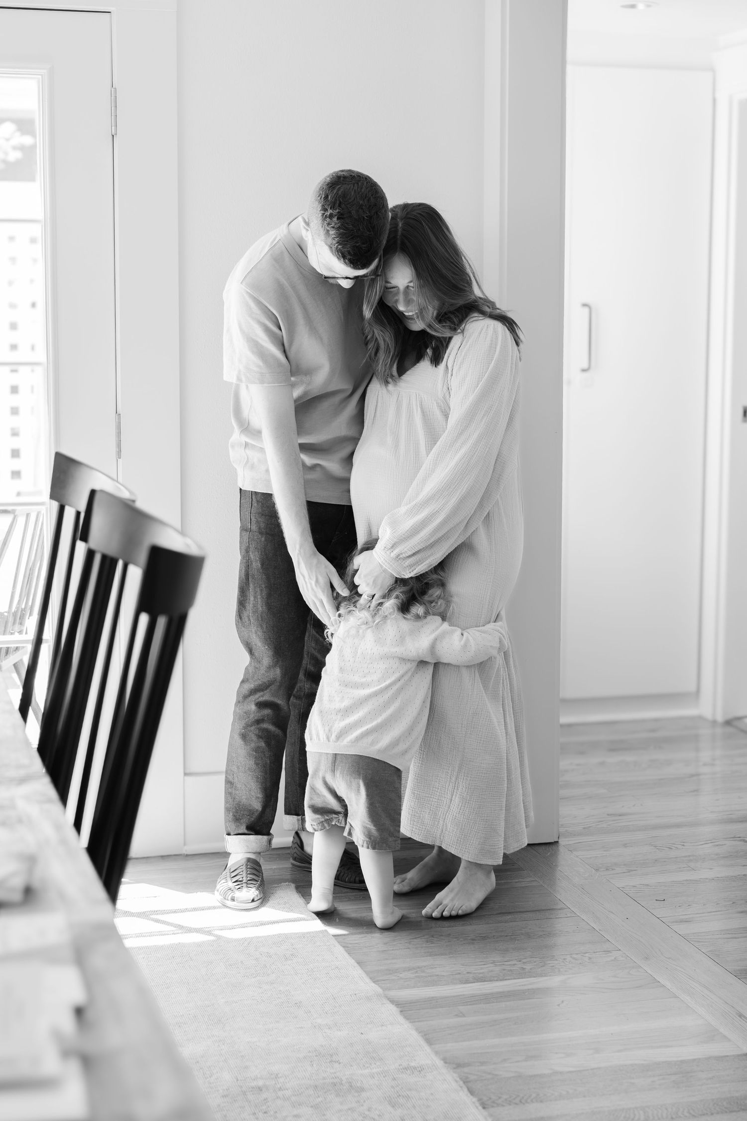 A couple interacts playfully in a bright indoor setting with hardwood floors.