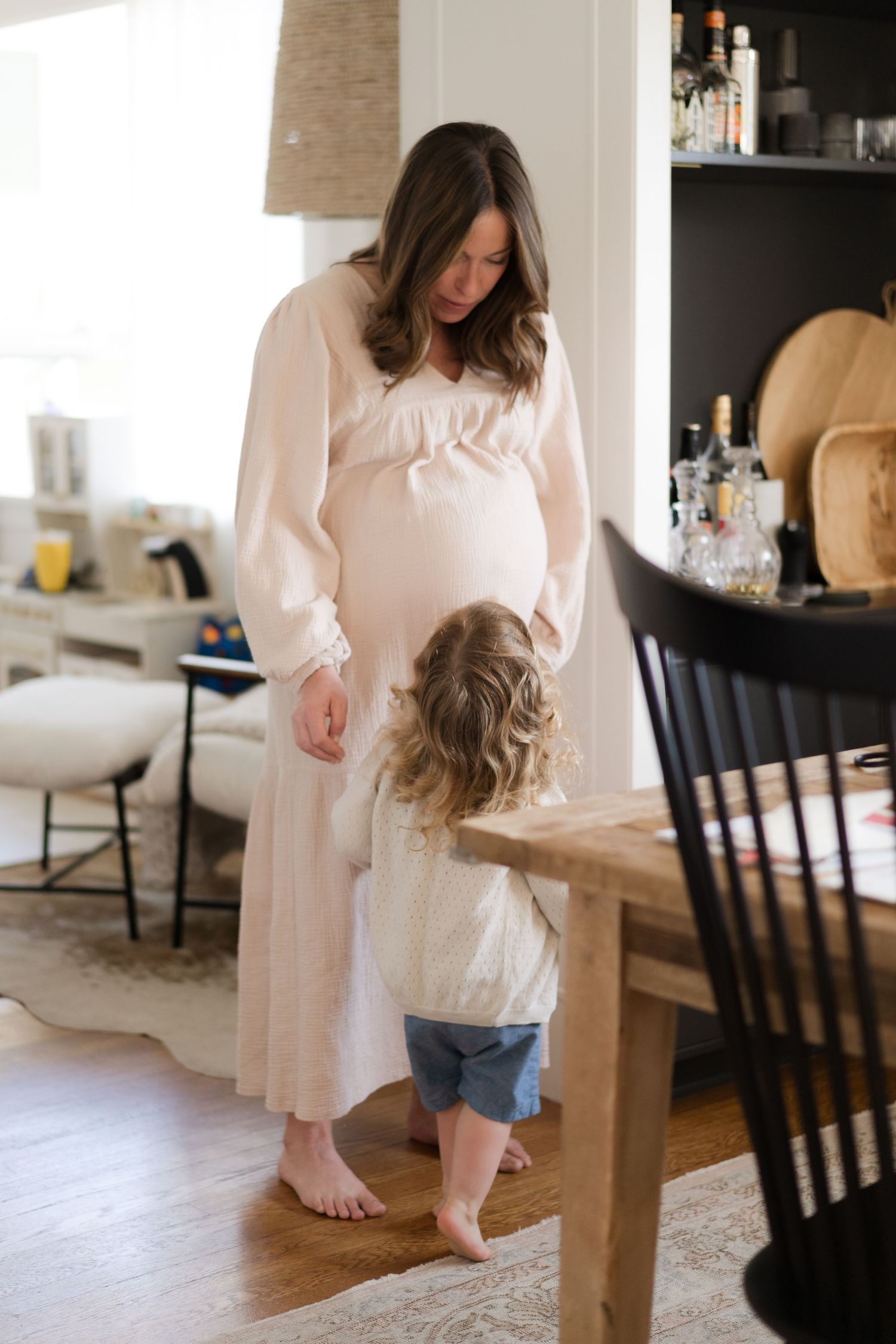 Parent and child interact playfully in bright modern living room with hardwood floors.