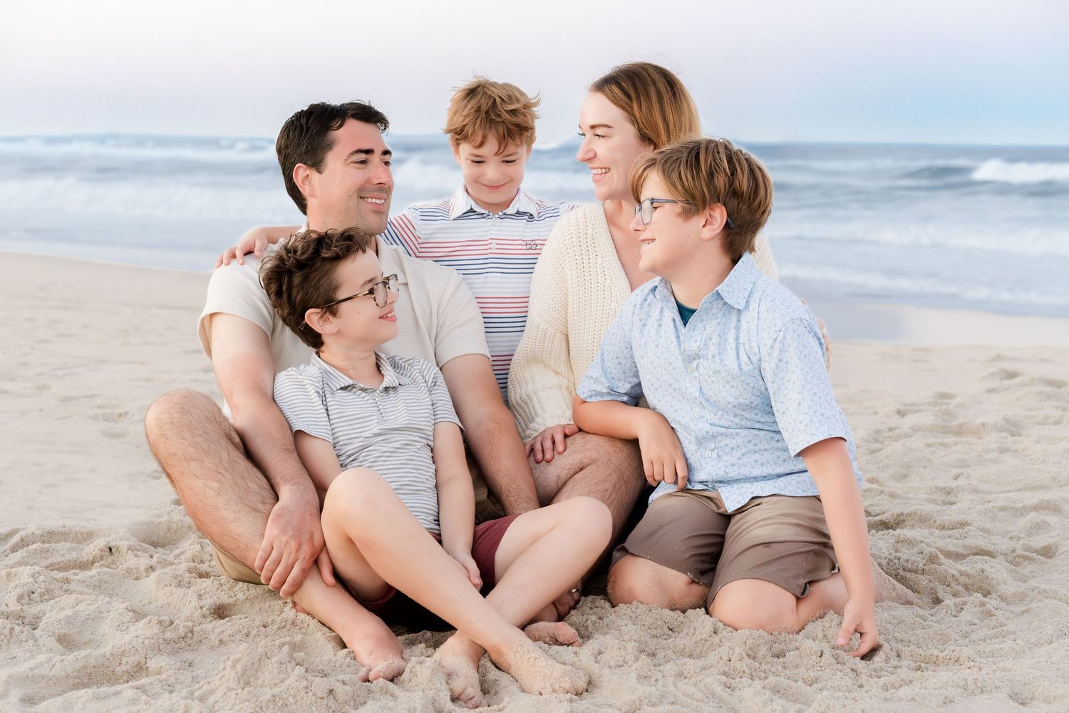 A candid moment of a family laughing together while sitting on the beach.