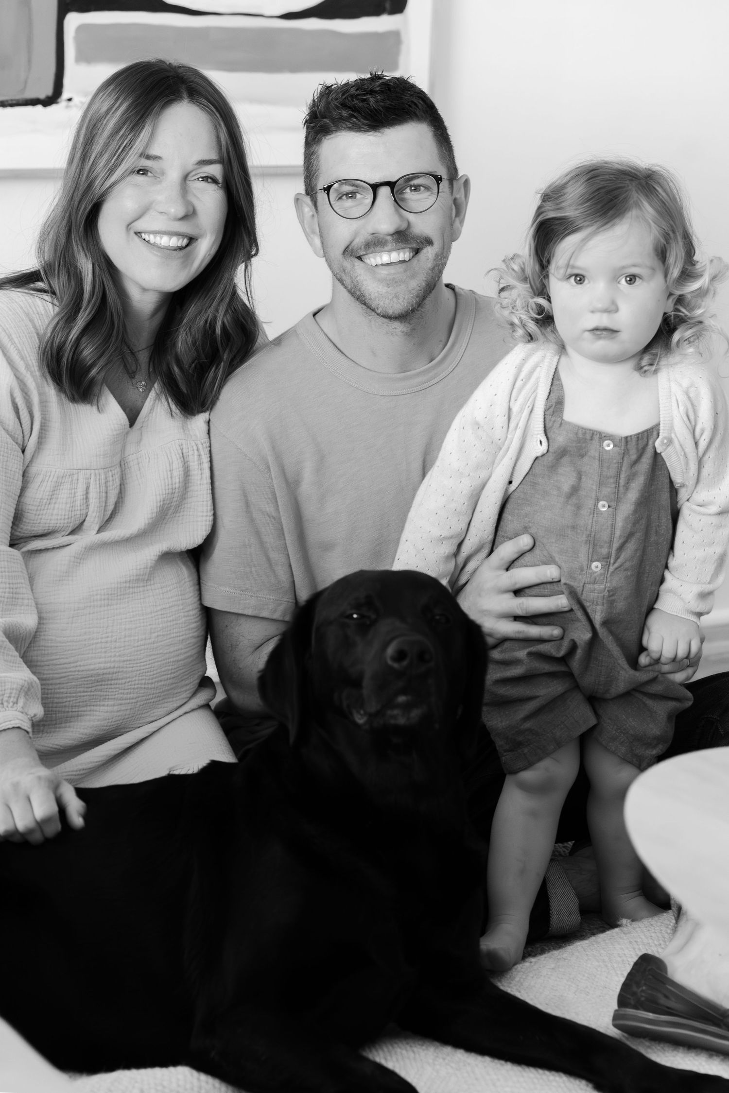 Black and white family photo showing relaxed moments with their pet dog.