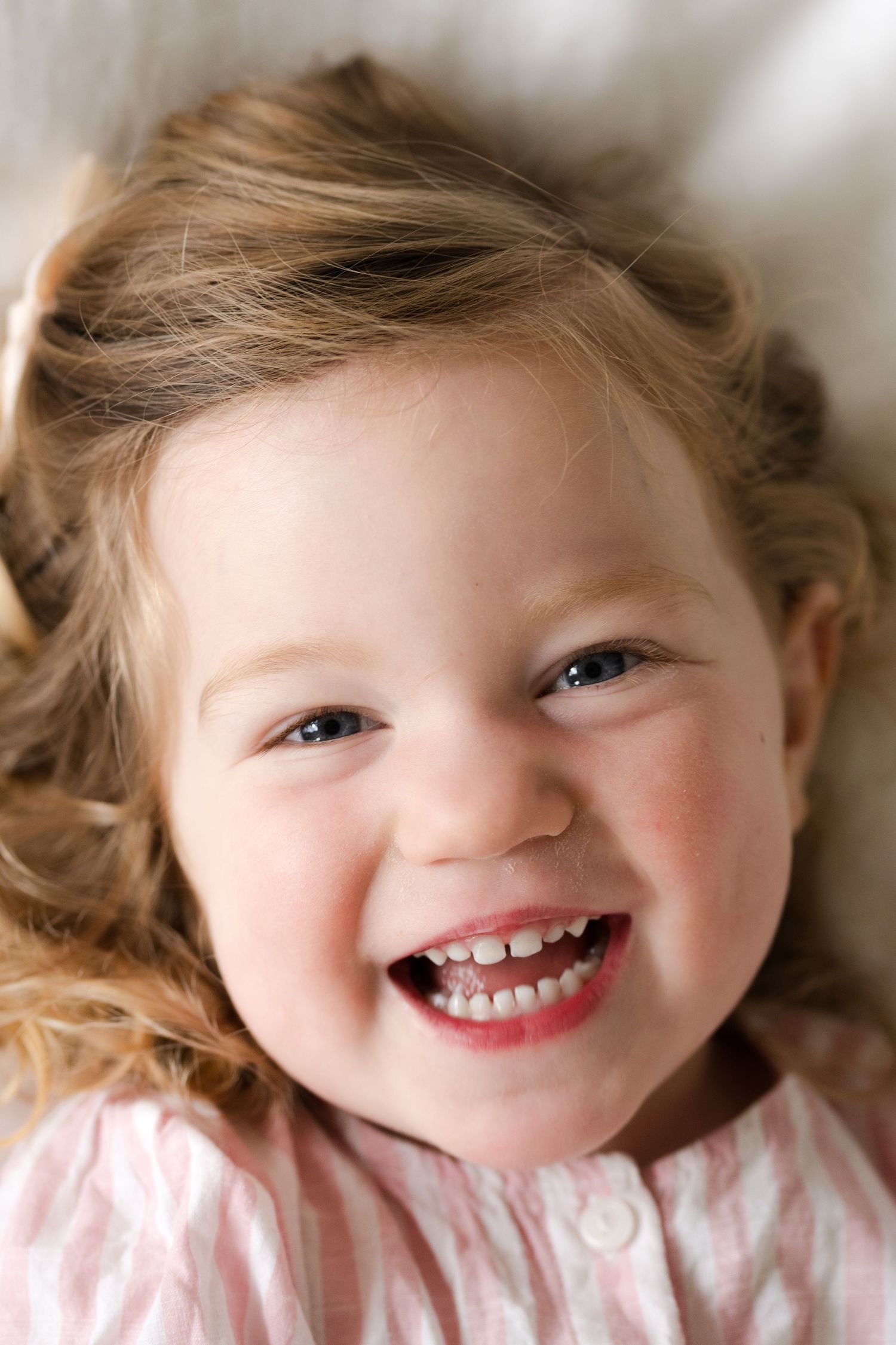 A joyful expression captured in a close-up portrait wearing a pink ruffled dress.