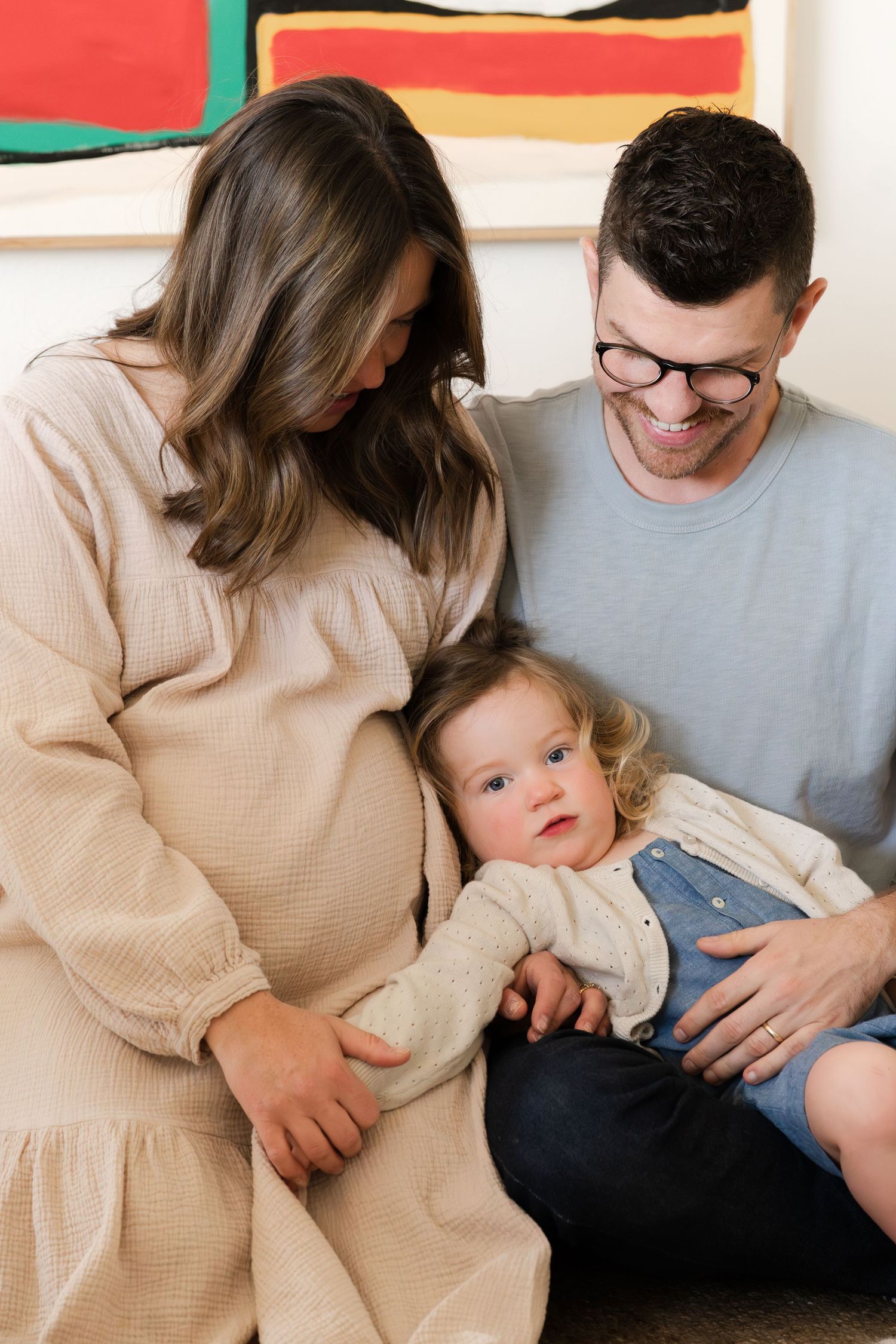 Family shares tender moments together on a couch with neutral-toned clothing.