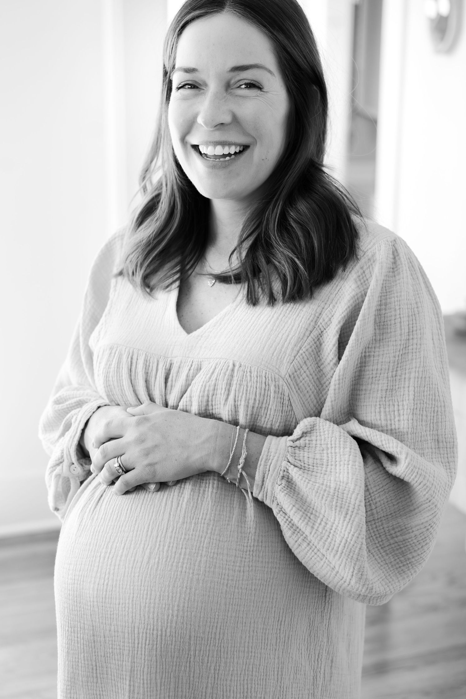 Maternity photos showing joyful moments and belly touches in a bright indoor setting.