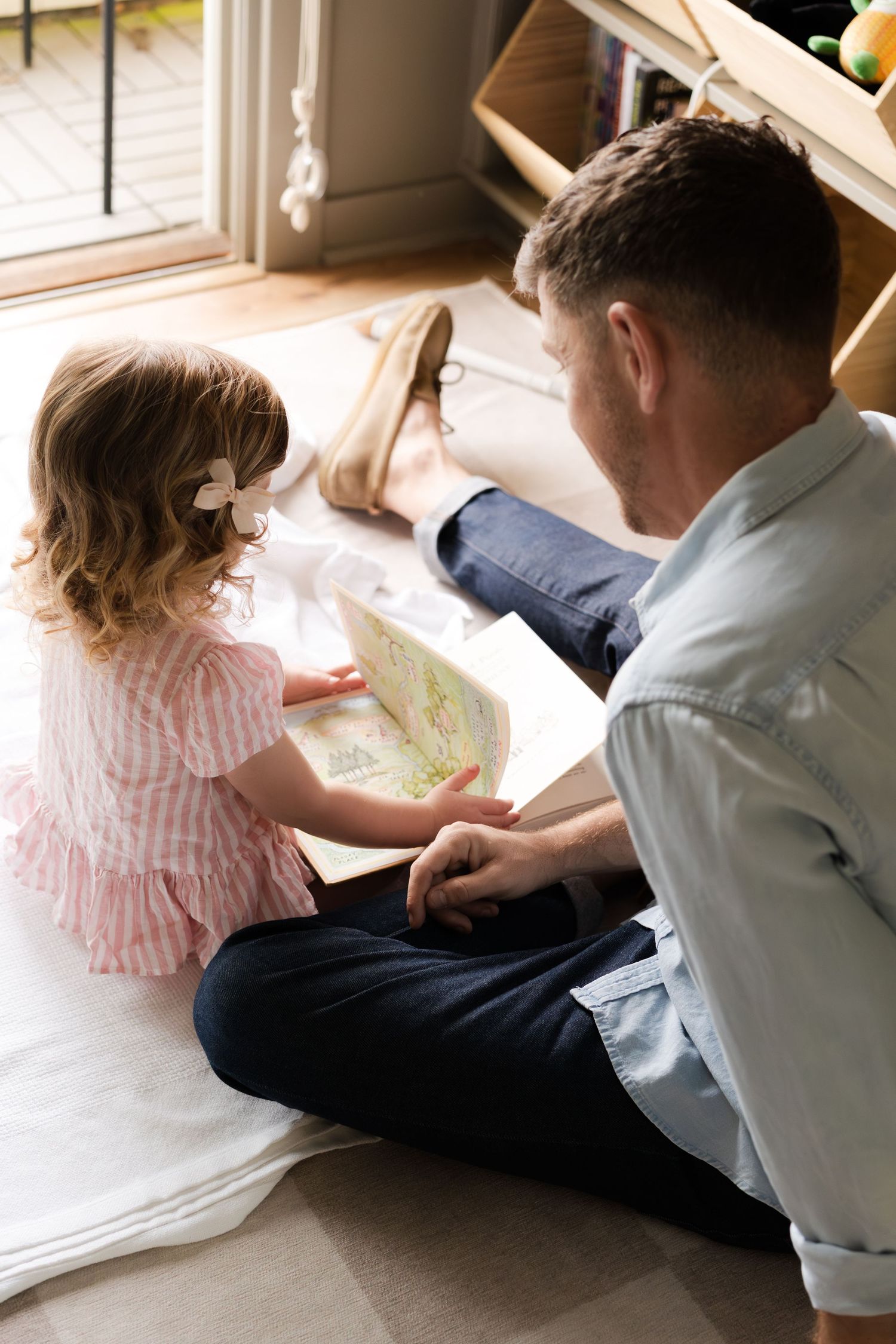 A heartwarming scene of shared storytime on a cozy floor near a window.