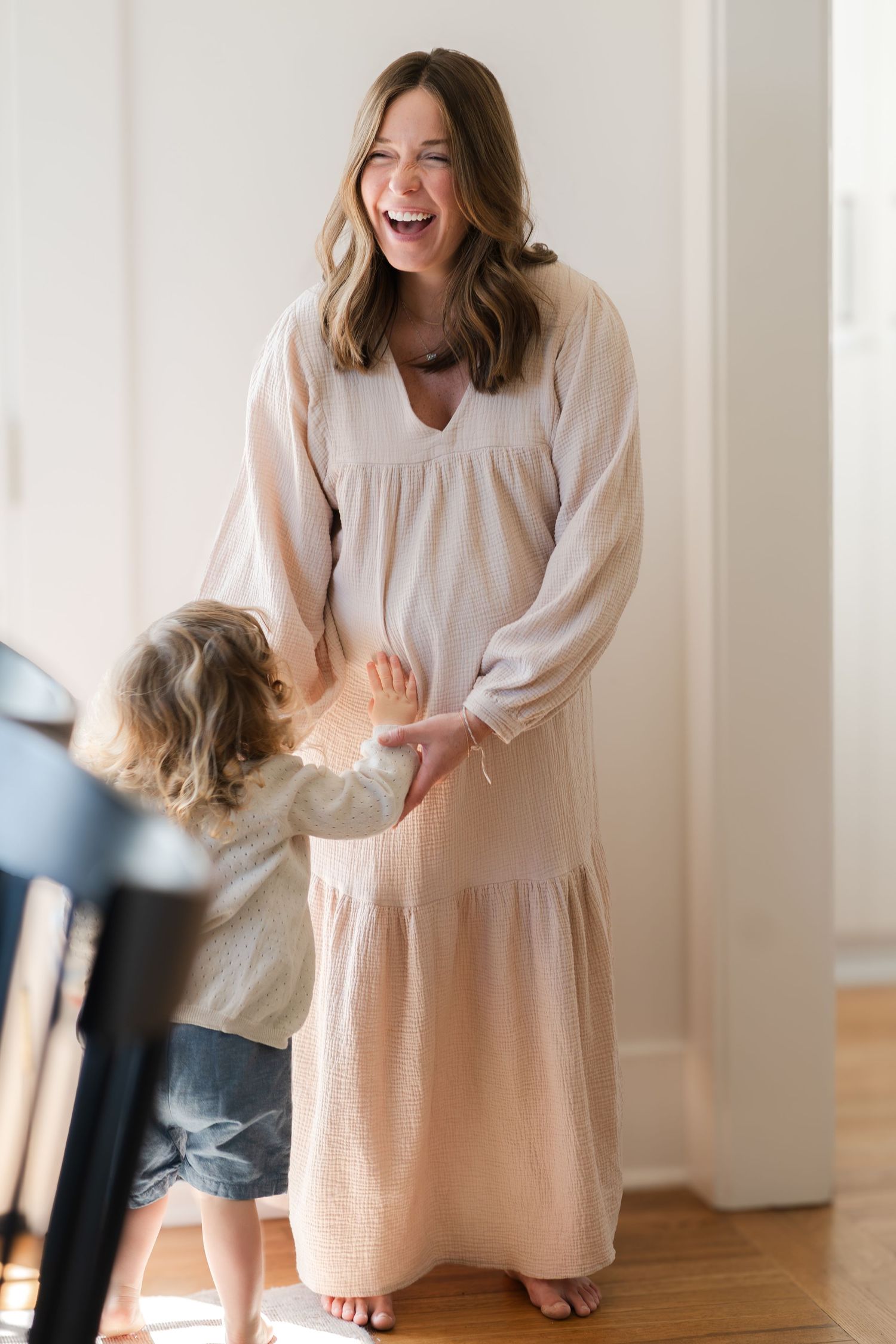 A heartwarming interaction between a parent in a flowing dress and child in casual wear.