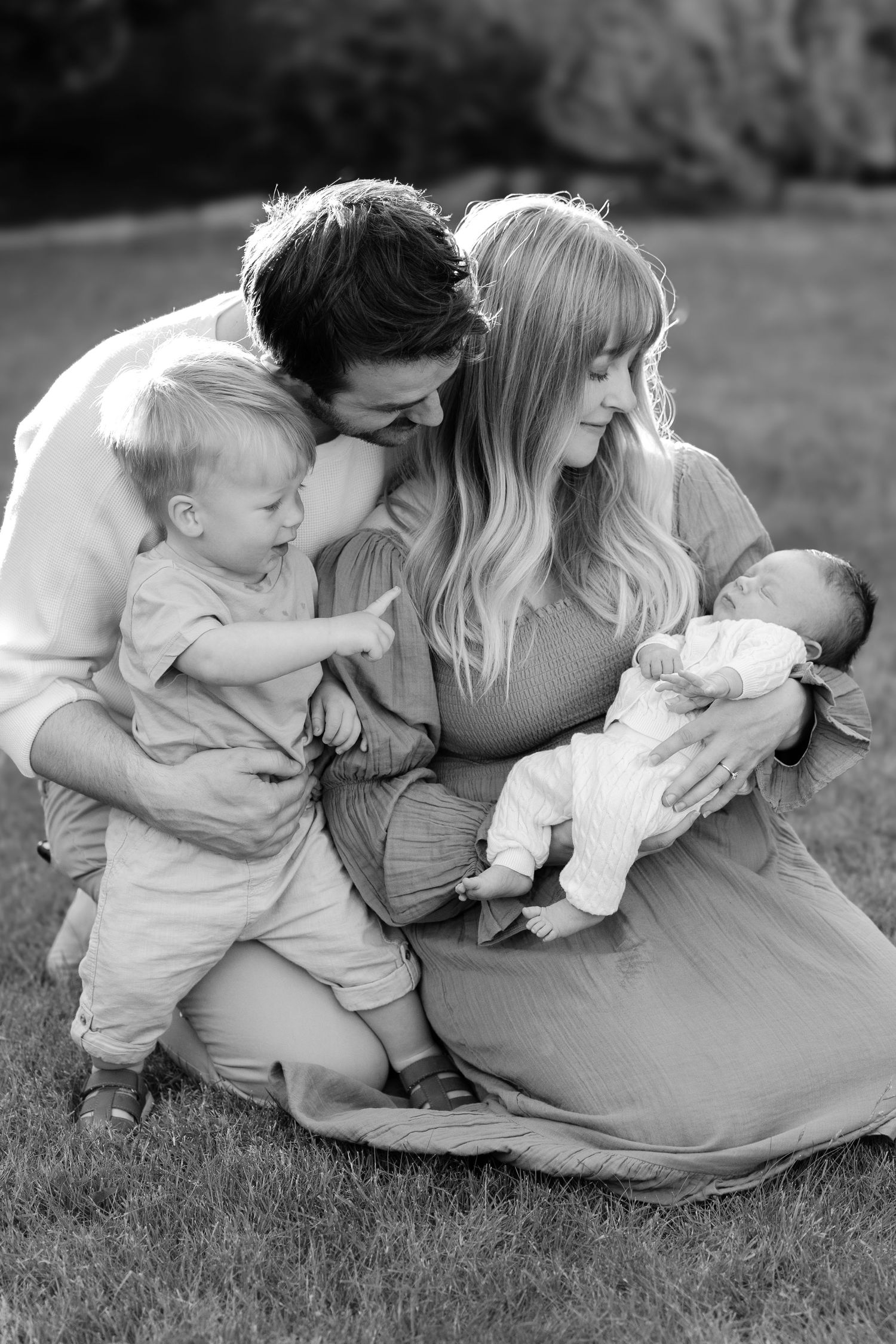 Black and white outdoor family photos showing parents and children lounging together on grass.
