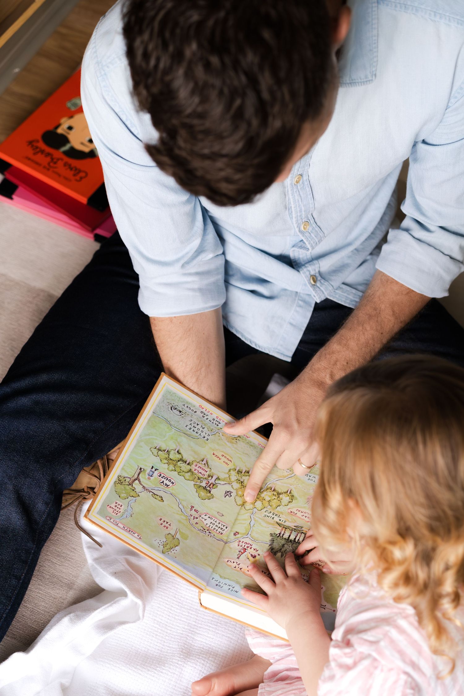 Parent and child looking at picture book together while sitting on floor.