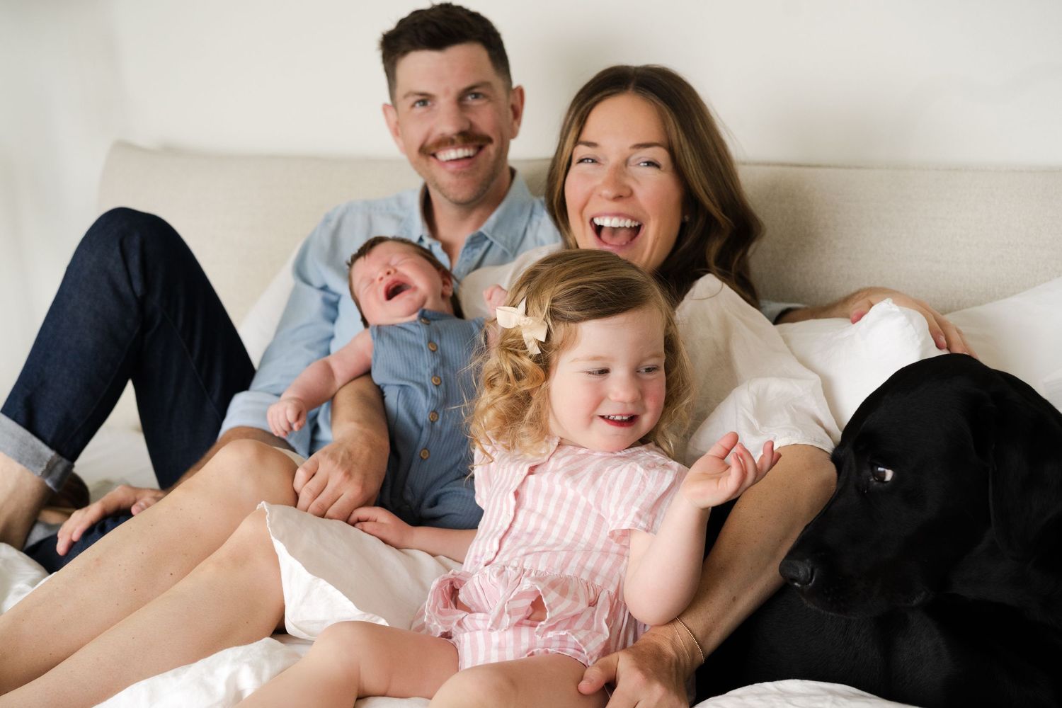 Candid family photo capturing genuine laughter and connection on bed.