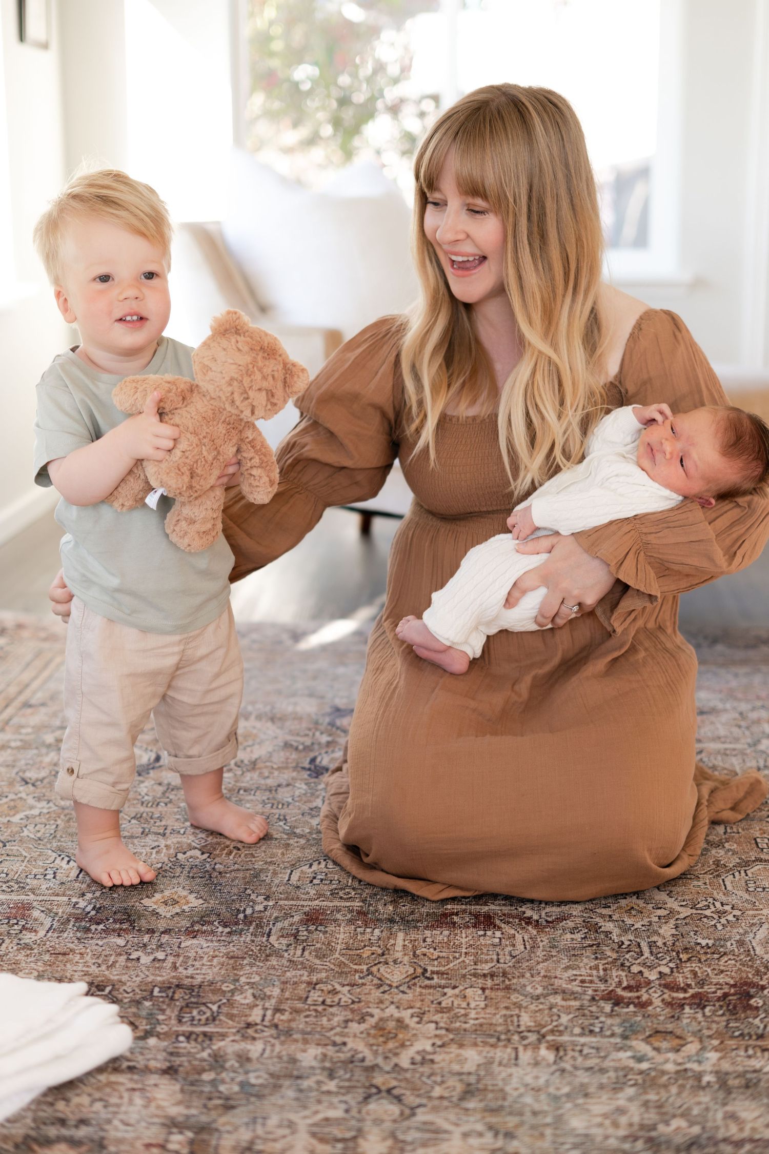 Candid family moments on a patterned rug showing a toddler playing while parents hold baby.