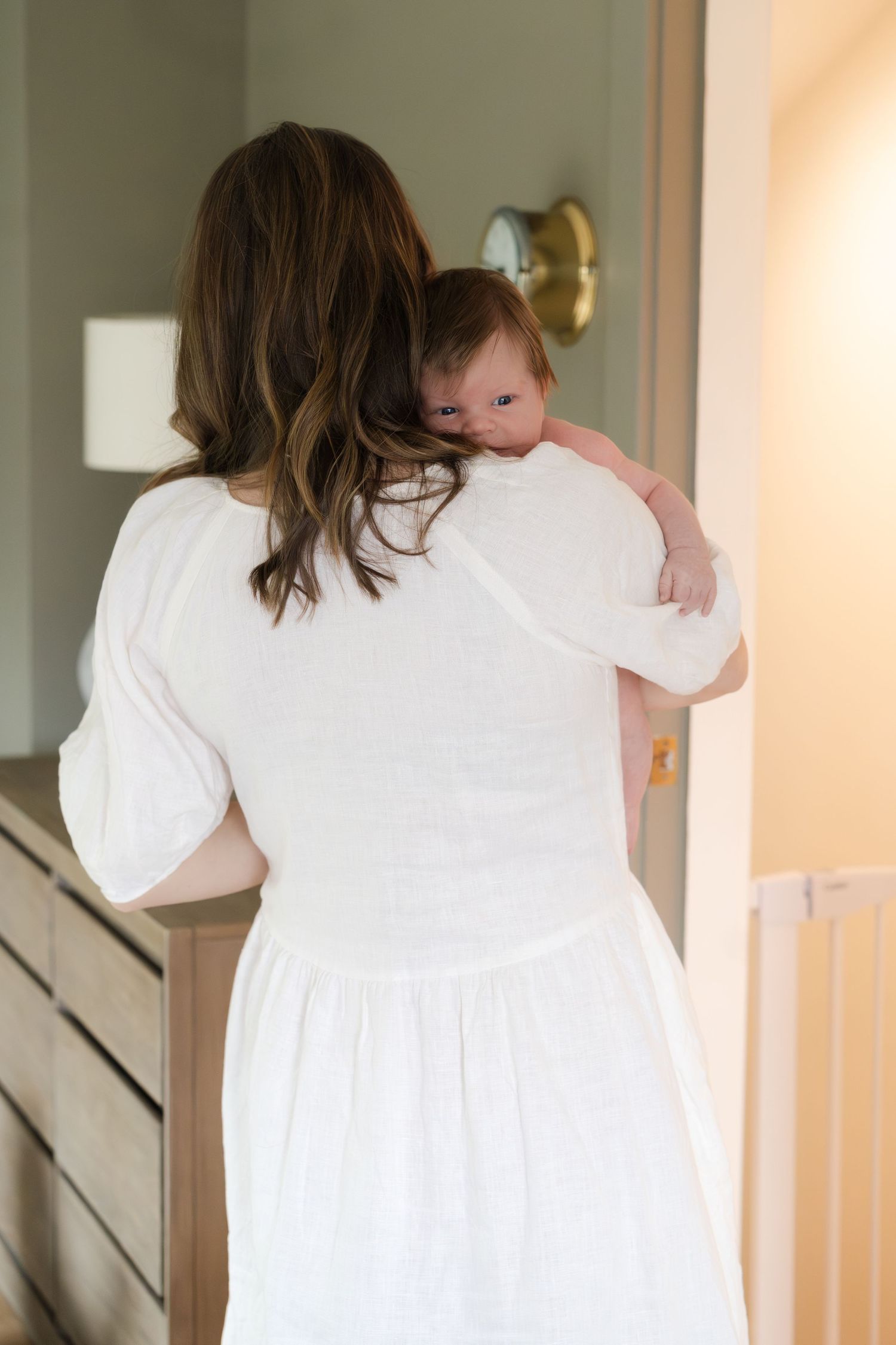 A gentle embrace in white dress carrying a baby up the stairs.
