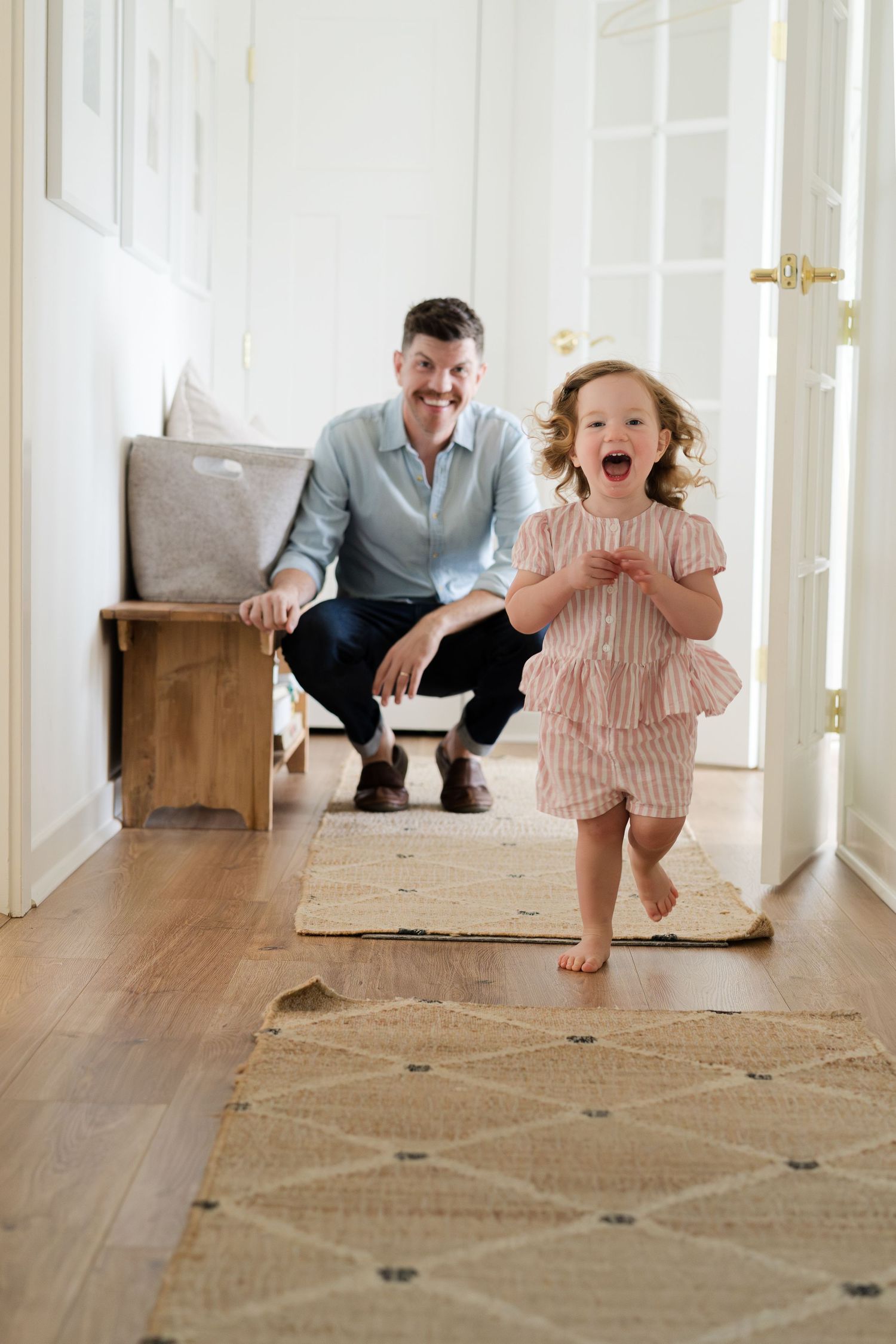 Energetic running and playing captured in a bright hallway with wooden floors.