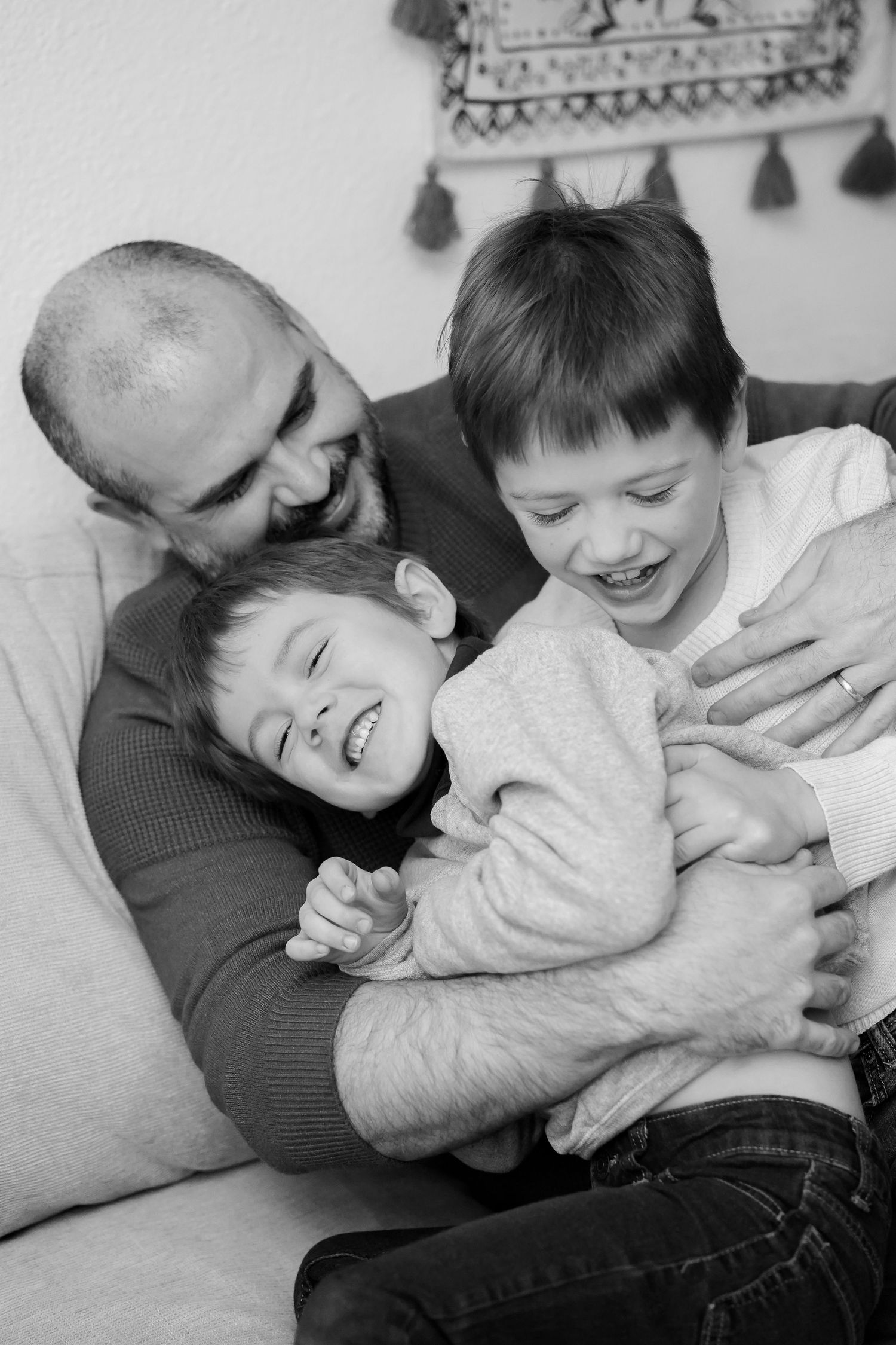 Candid black and white photo of joyful playtime on a couch.