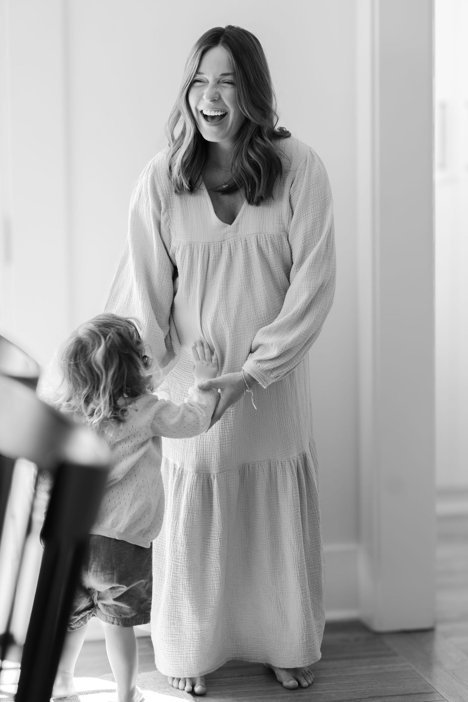 A joyful moment captured in black and white as a parent and child interact in a bright room.