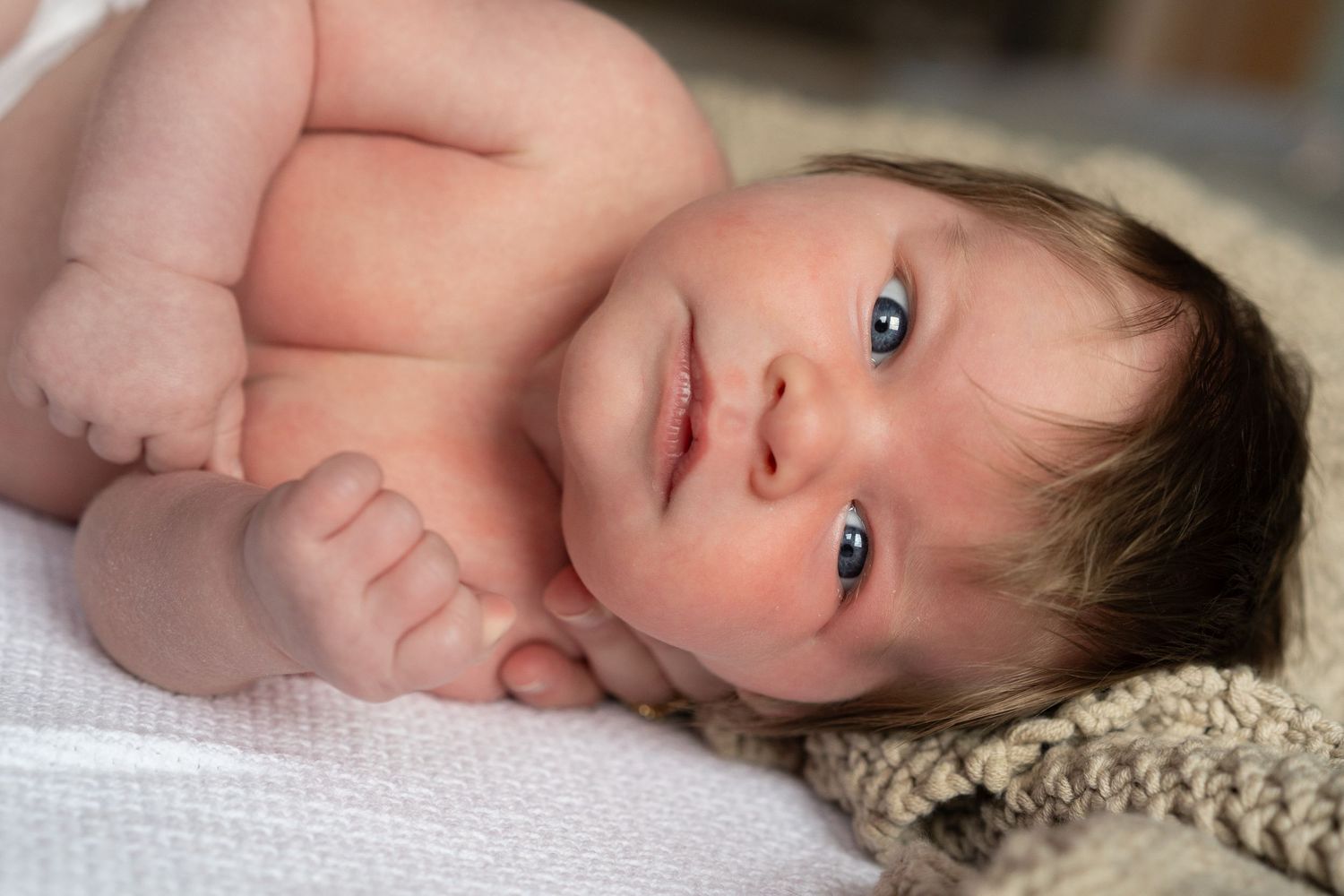 Series of peaceful newborn baby portraits on soft white bedding.