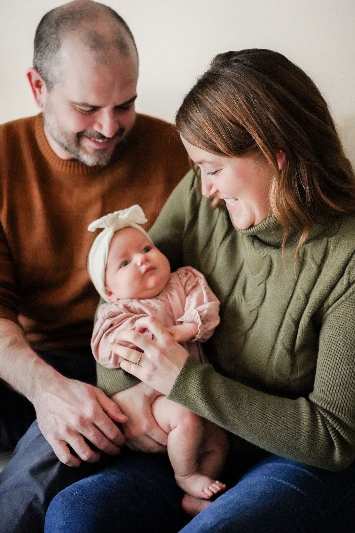 Couple in casual sweaters sharing tender moment with infant.
