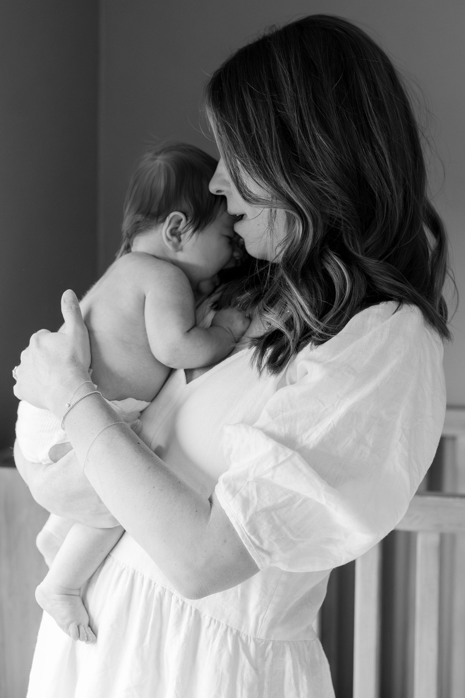 A tender moment between parent and infant in a black and white photograph.