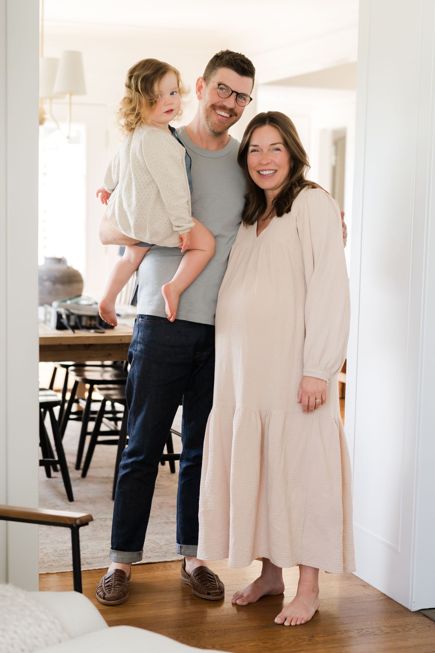 A casual family portrait showing three people standing together in a bright interior.