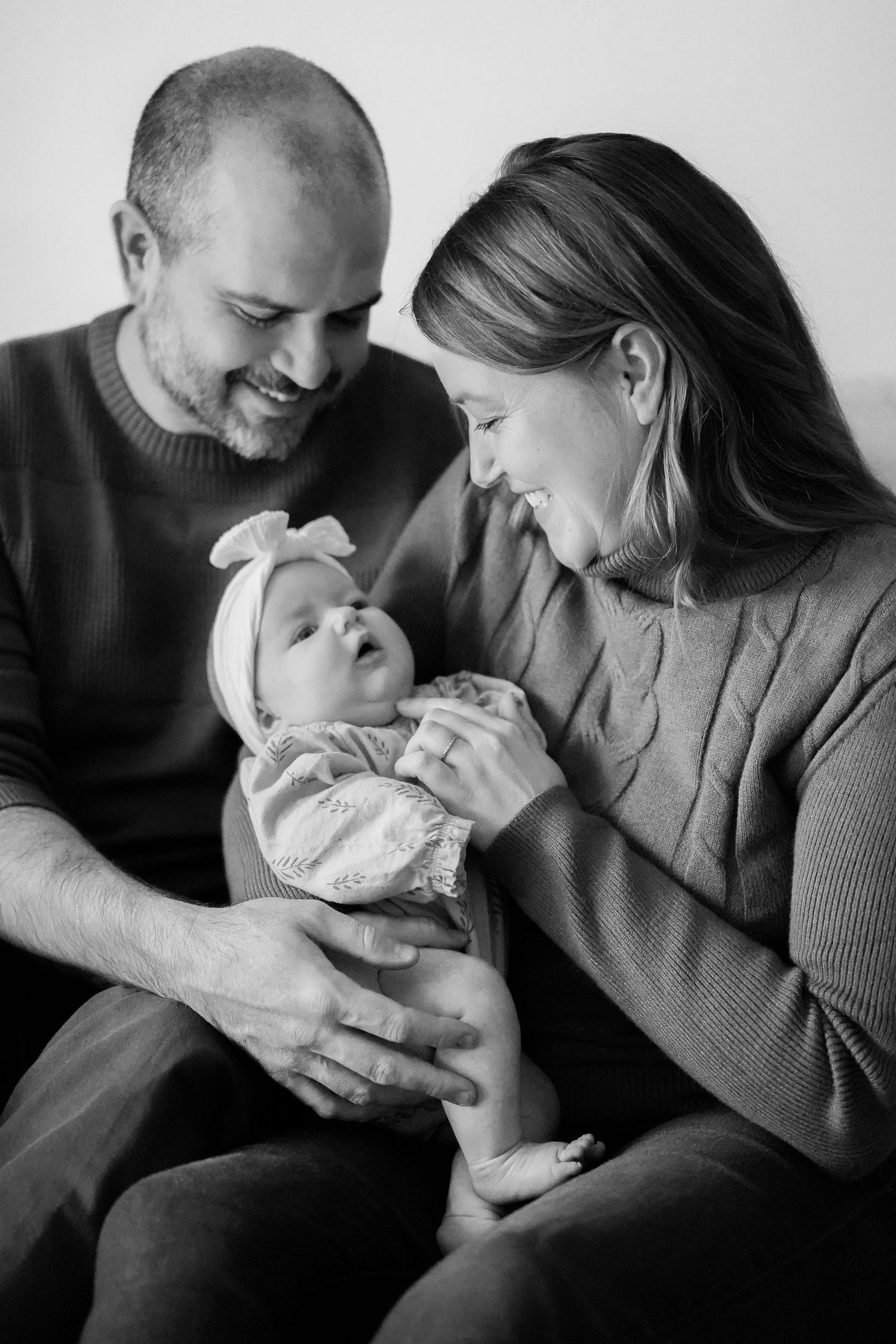 Black and white intimate portrait of parents gazing lovingly at their baby.