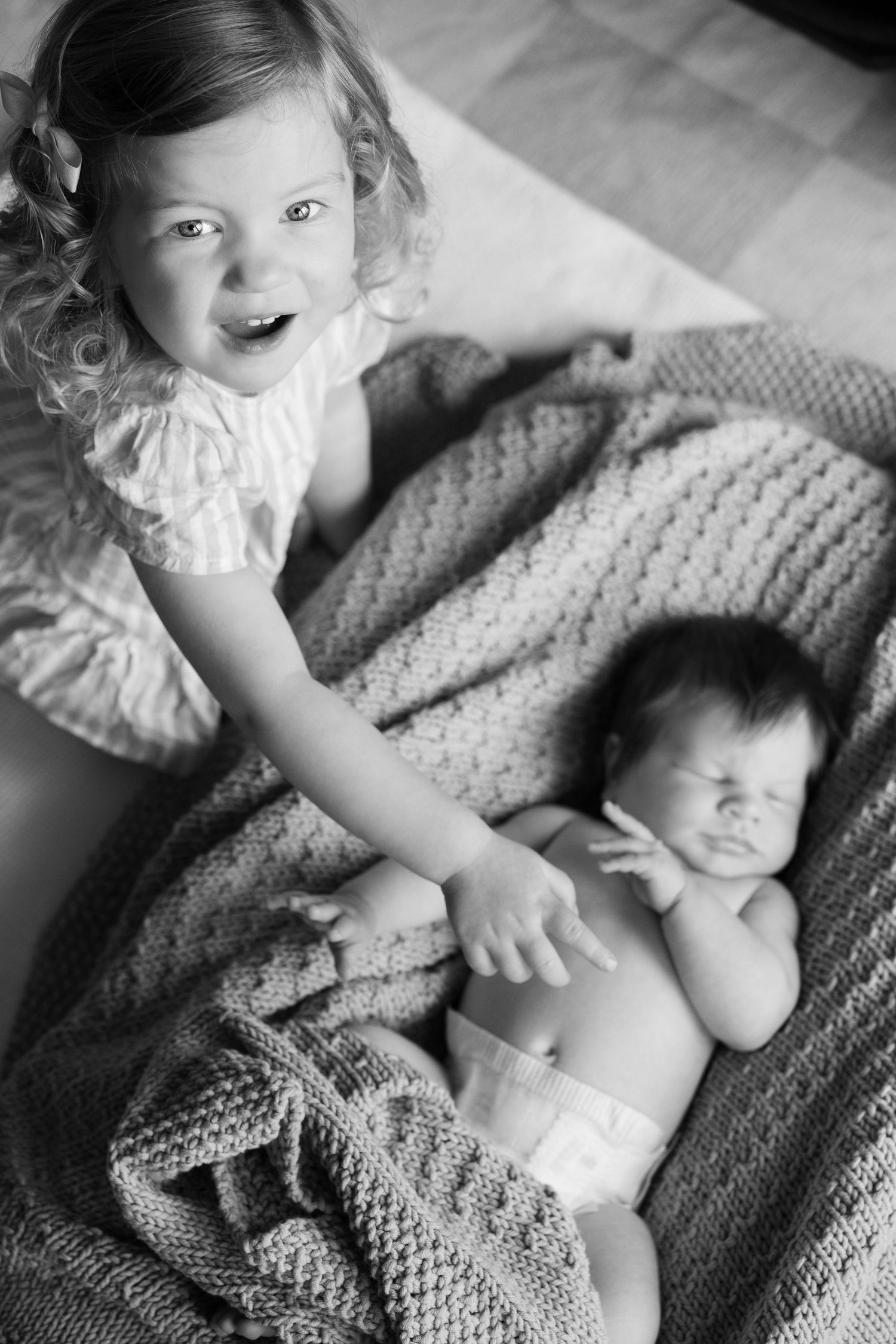 Siblings bonding together on soft knitted blanket during intimate photo shoot.