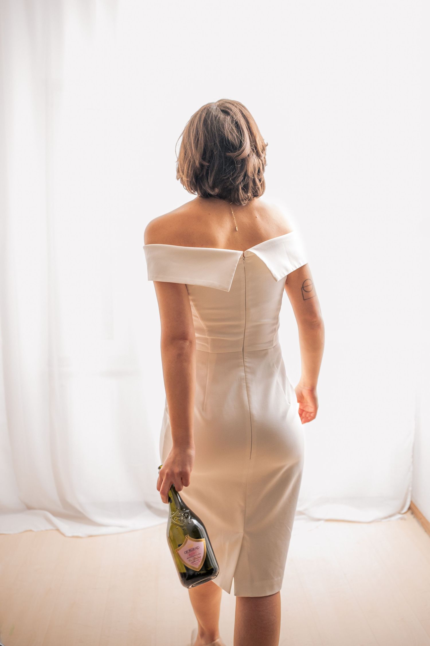 Rückenansicht der Braut im schlichten Brautkleid, elegantes Brautshooting mit natürlichem Fensterlicht