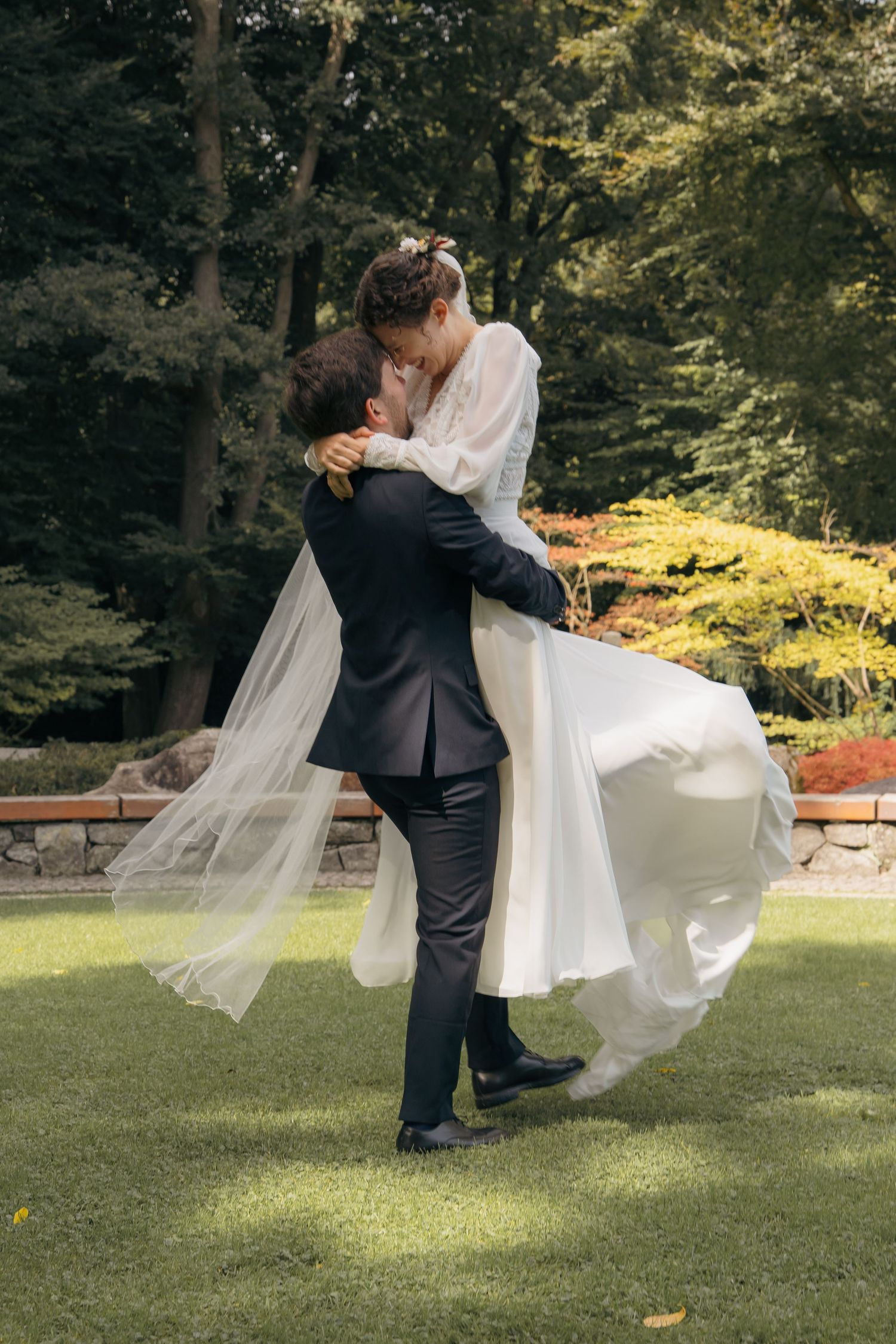Bräutigam hebt die Braut beim First Look im Park hoch, emotionaler Moment einer Hochzeit im Grünen