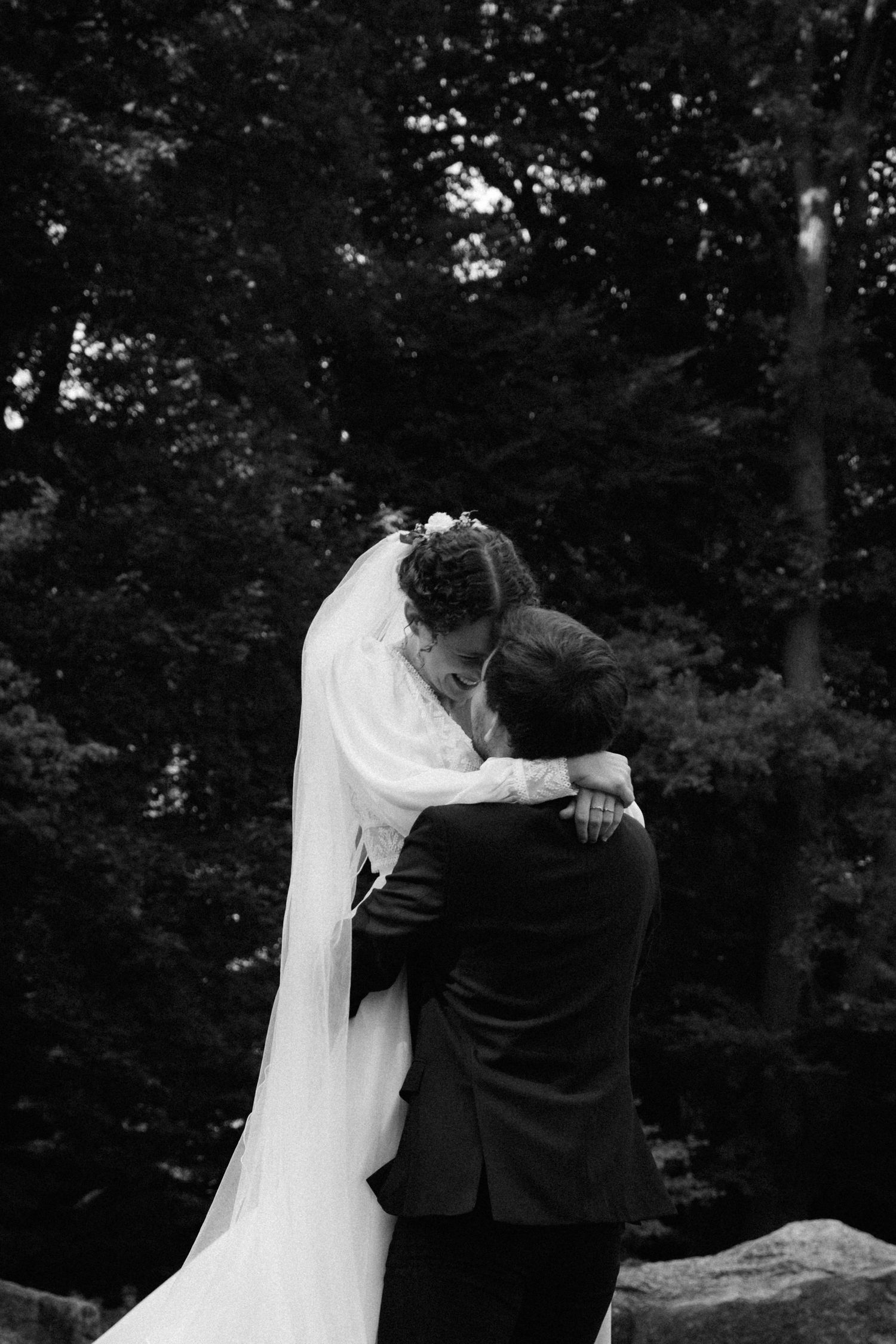 Inniger First Look Moment eines Brautpaares im Park, Braut umarmt den Bräutigam von vorne