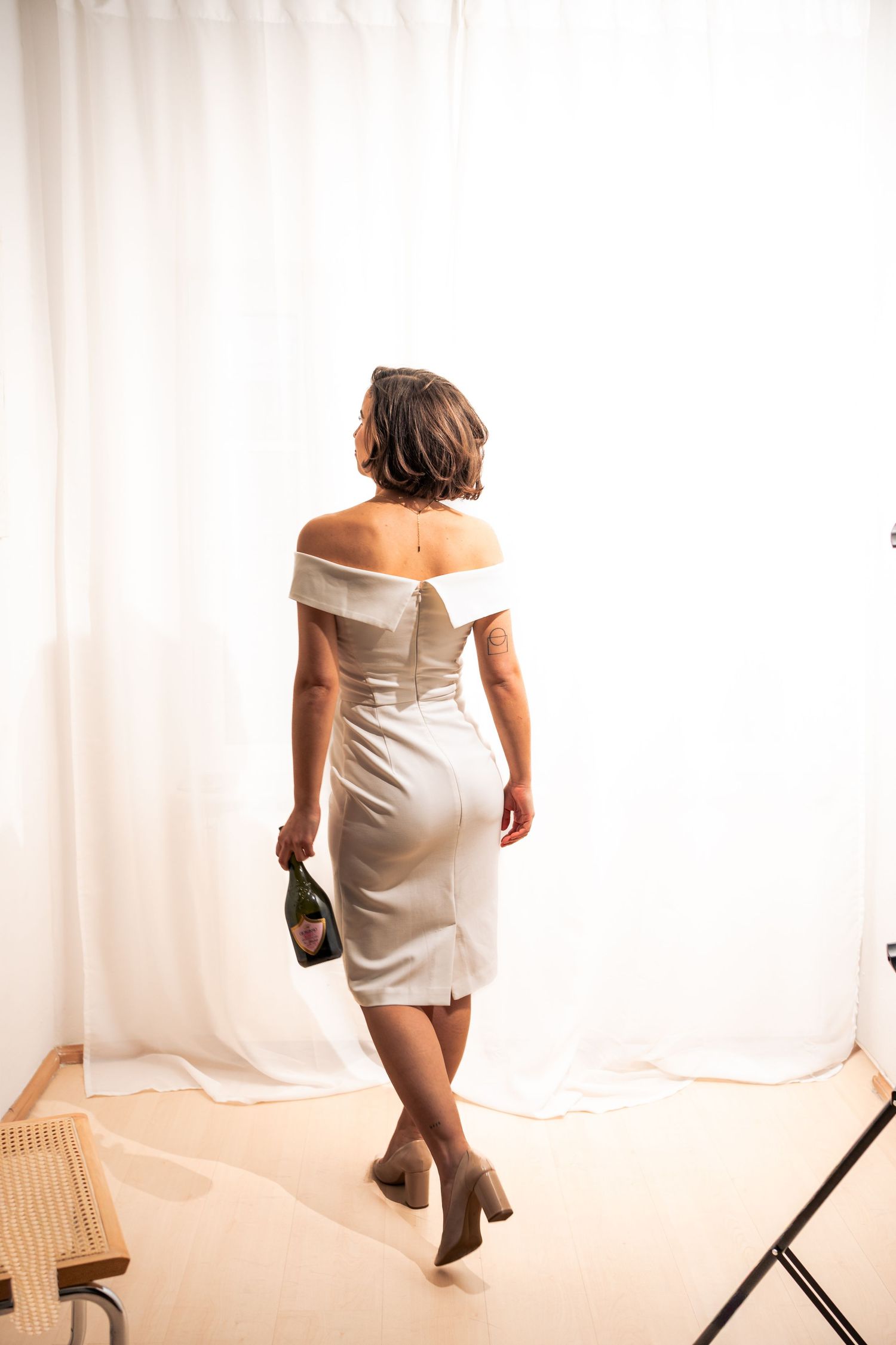Braut geht mit Sektflasche durch hellen Raum, minimalistisches Brautshooting mit Bewegung