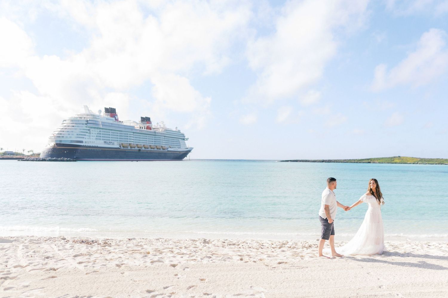 Cruise ship anchored near pristine white sand beach with turquoise waters in tropical paradise.