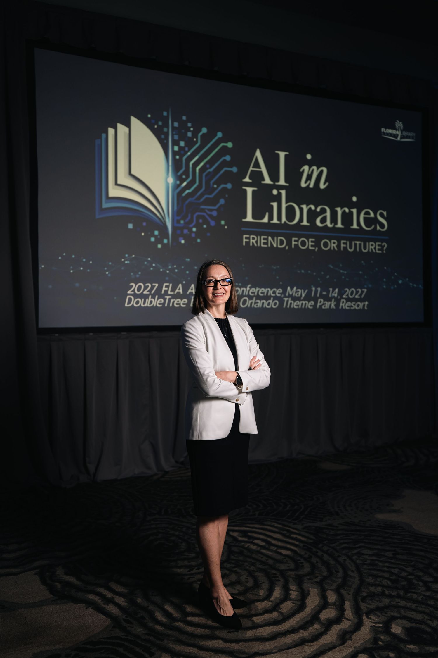 Professional conference portrait of a businesswoman standing in front of an “AI in Libraries” presentation screen at the Florida Library Ass