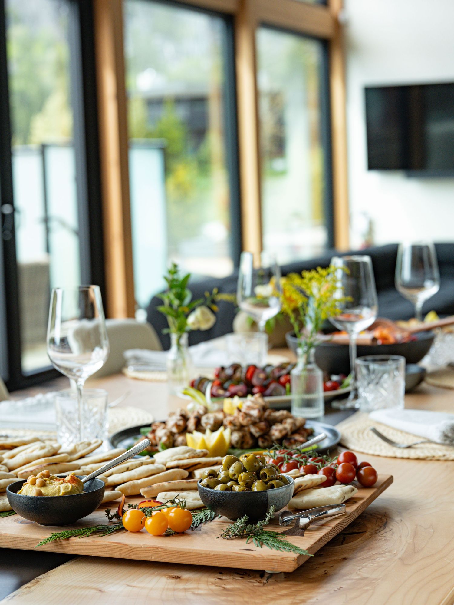 Elegant dining table spread with charcuterie board, olives, vegetables and wine glasses.