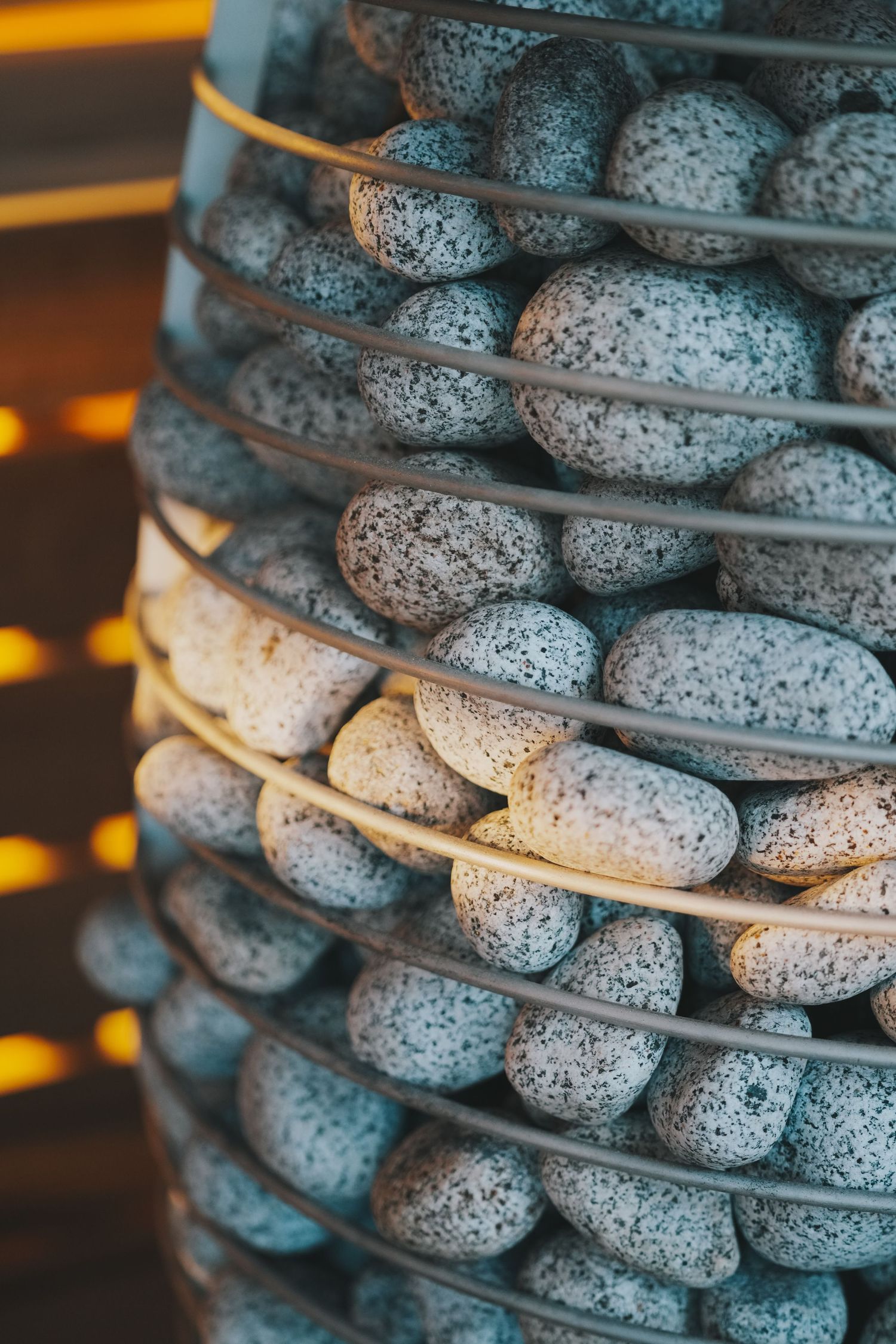 Close-up of stacked granite sauna stones arranged in metal cage of a traditional Finnish sauna heater.